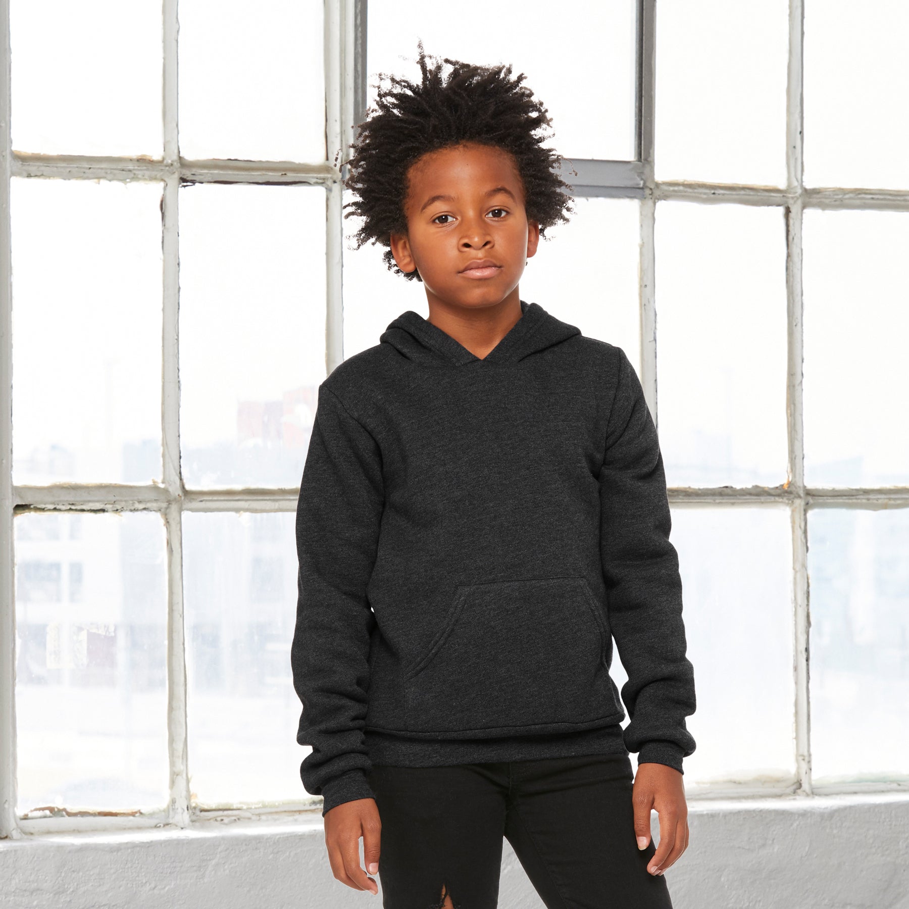 Young boy wearing a Bella+Canvas Youth Poly-Cotton Fleece Pullover Hoodie in Dark Grey Heather.