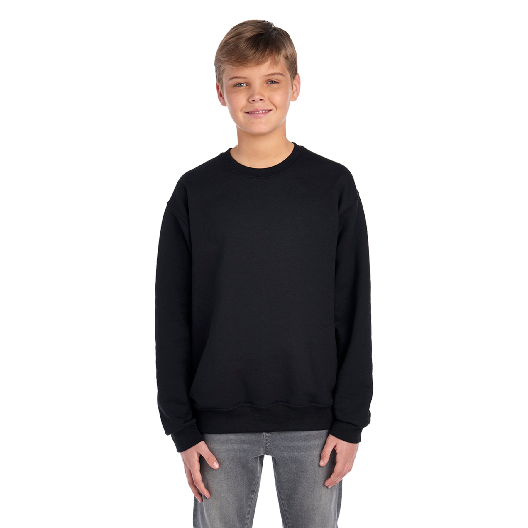 A youth model wearing a black Jerzees NuBlend® Youth Sweatshirt with grey jeans, isolated on a white background.
