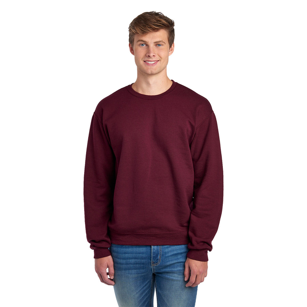 A man wearing a maroon Jerzees NuBlend® Adult Sweatshirt with blue jeans against a white background.
