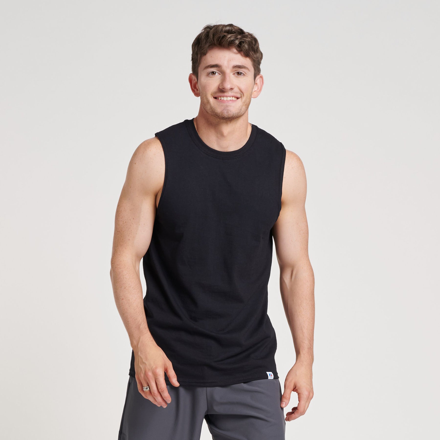A man wearing a black Russell Athletic DRI-POWER Performance unisex muscle t-shirt against a plain studio background.