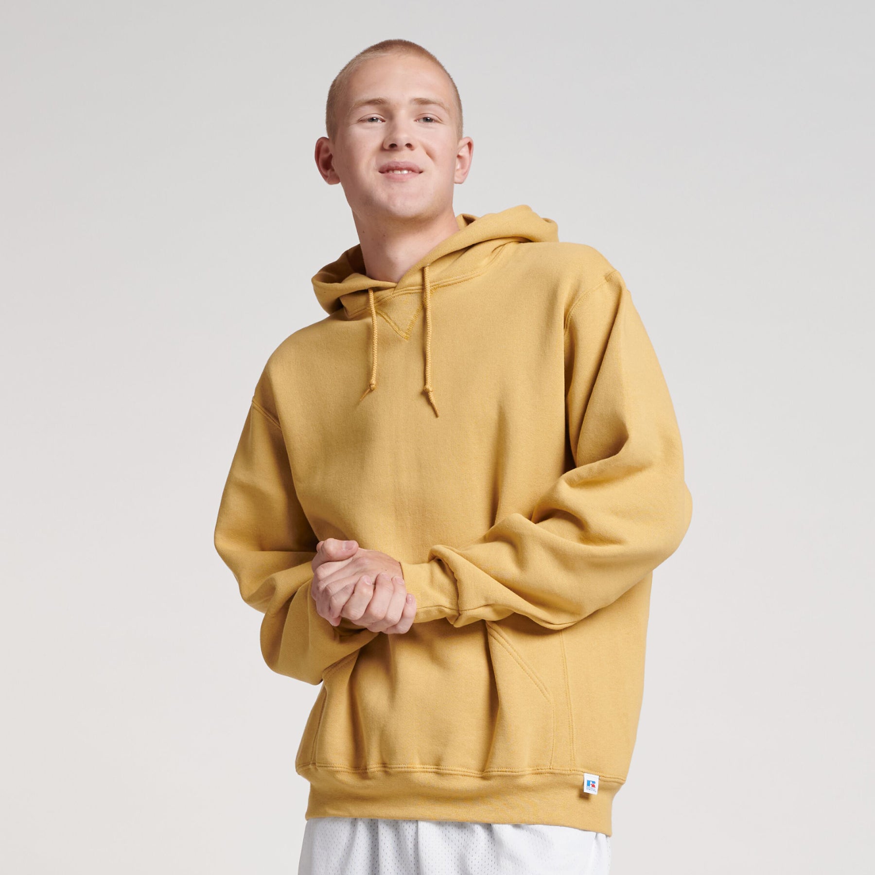 A person wearing a Russell Athletic DRI-POWER Adult Fleece Unisex Hoodie in almond color.