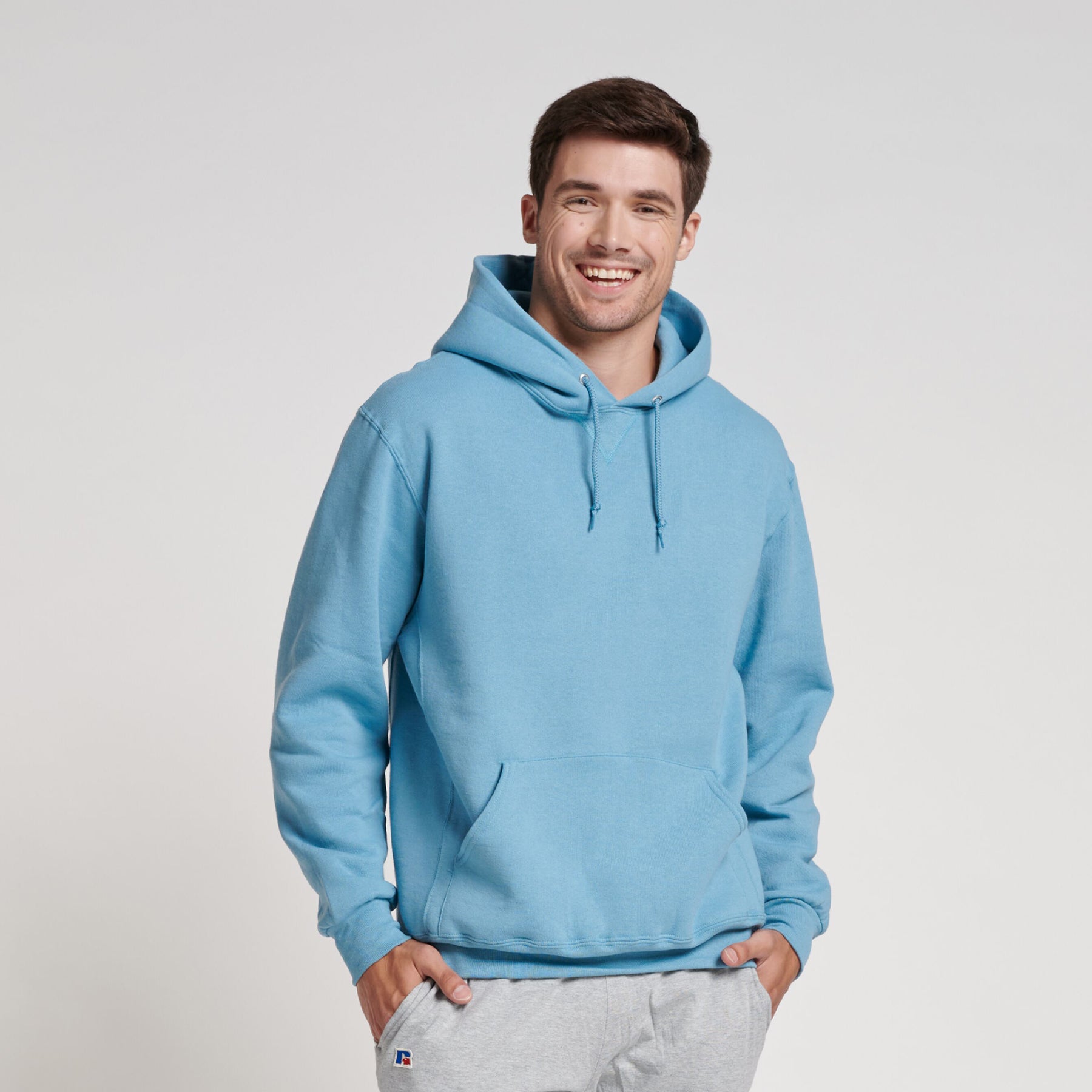 A man wearing a Russell Athletic DRI-POWER Adult Fleece Unisex Hoodie in Arctic Blue.
