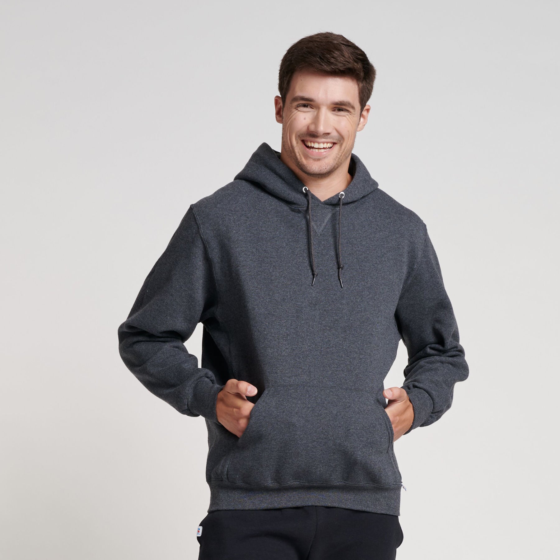 A smiling man wearing a Russell Athletic DRI-POWER Adult Fleece Unisex Hoodie in Black Heather.