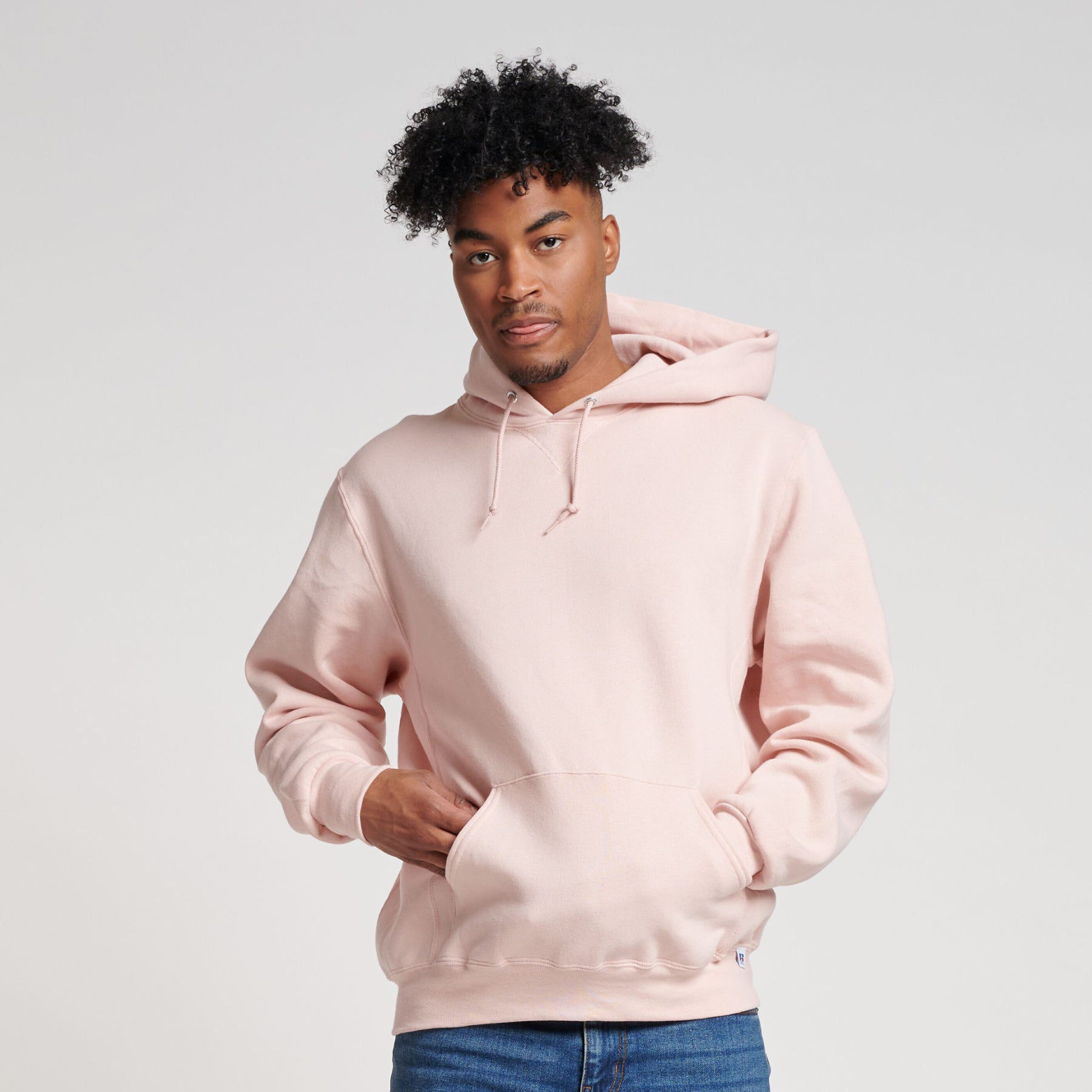 Man wearing a Russell Athletic DRI-POWER Adult Fleece Unisex Hoodie in blush pink against a white background.