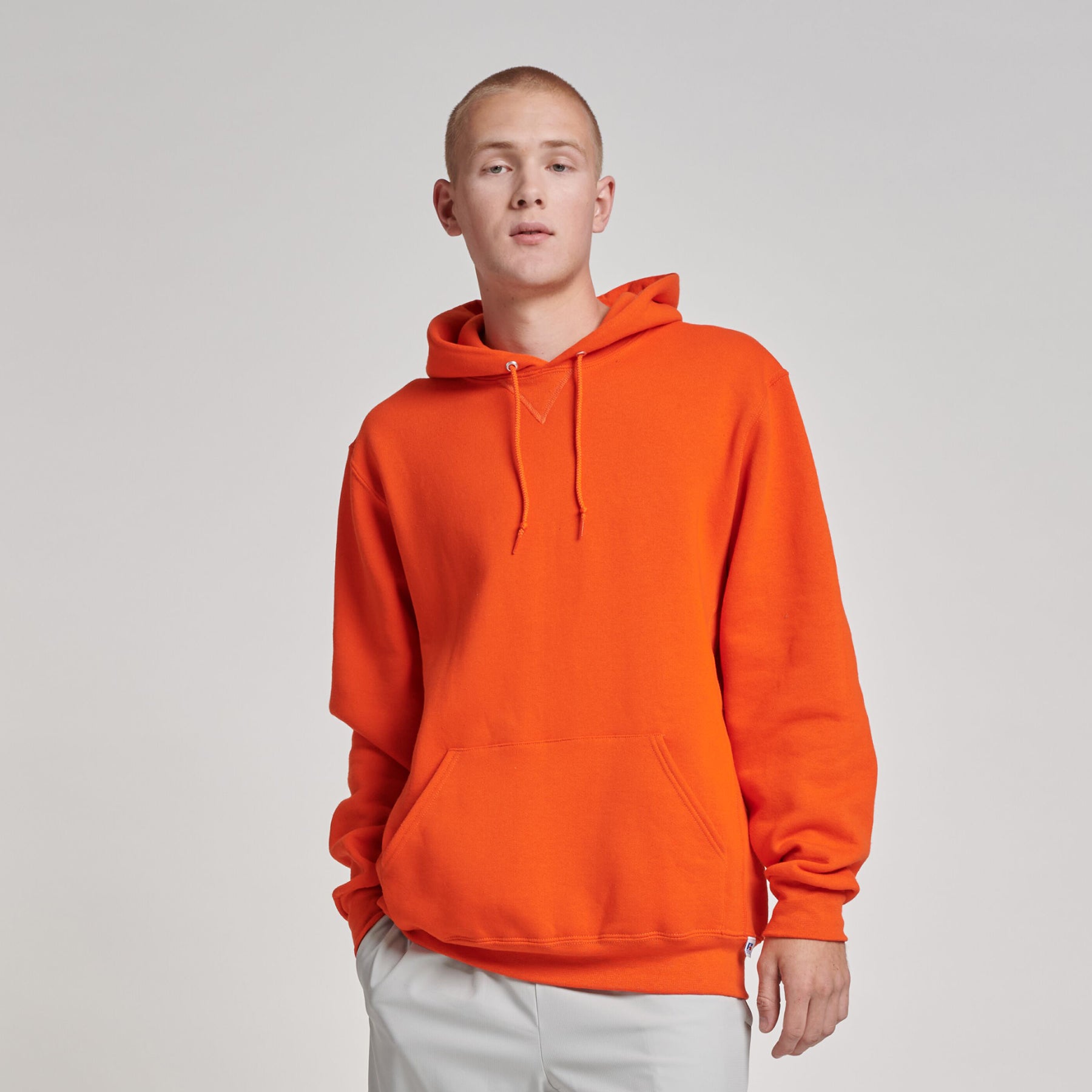 Man wearing a burnt orange Russell Athletic DRI-POWER Adult Fleece Unisex Hoodie against a plain grey background.