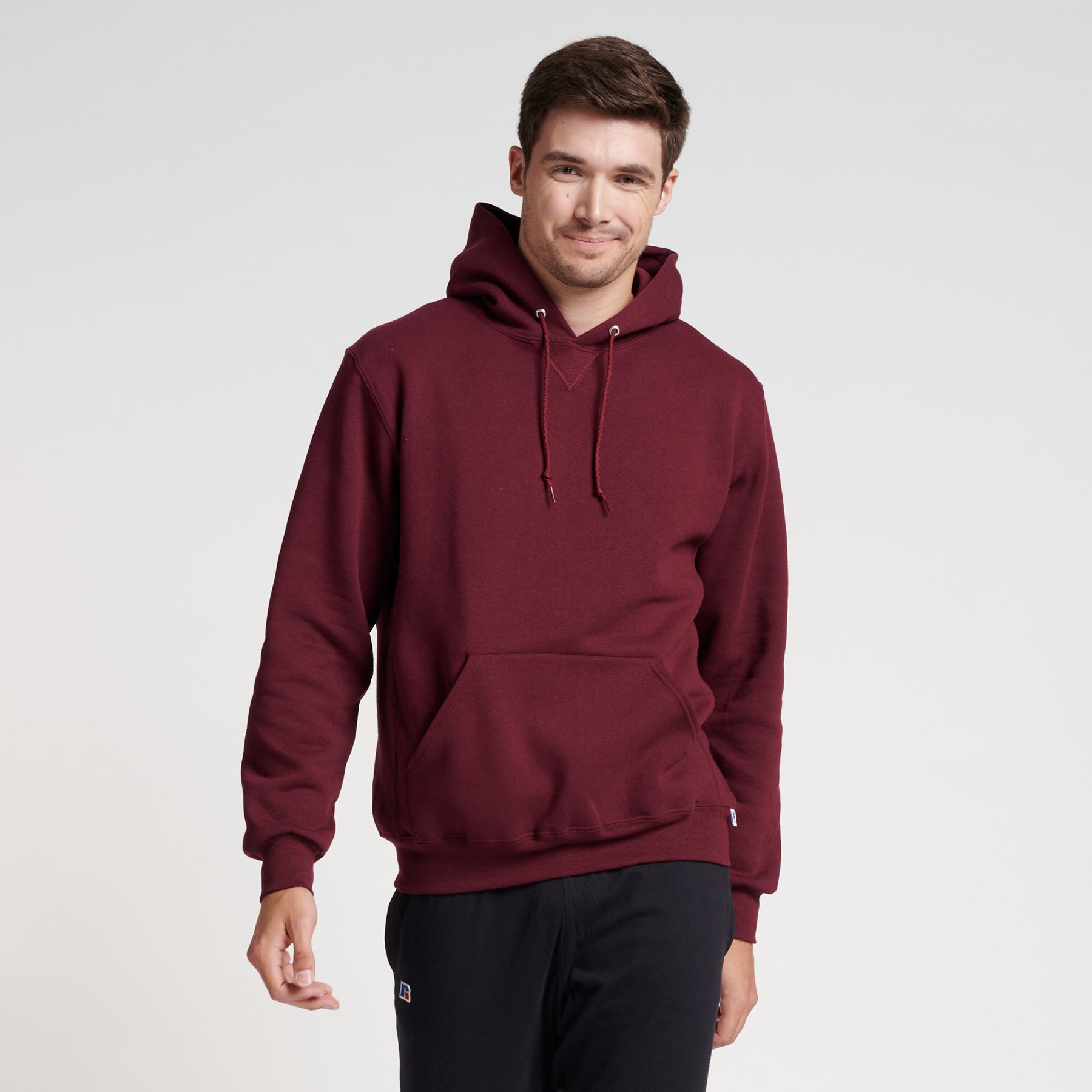 A man wearing a maroon Russell Athletic DRI-POWER Adult Fleece Unisex Hoodie against a plain white background.