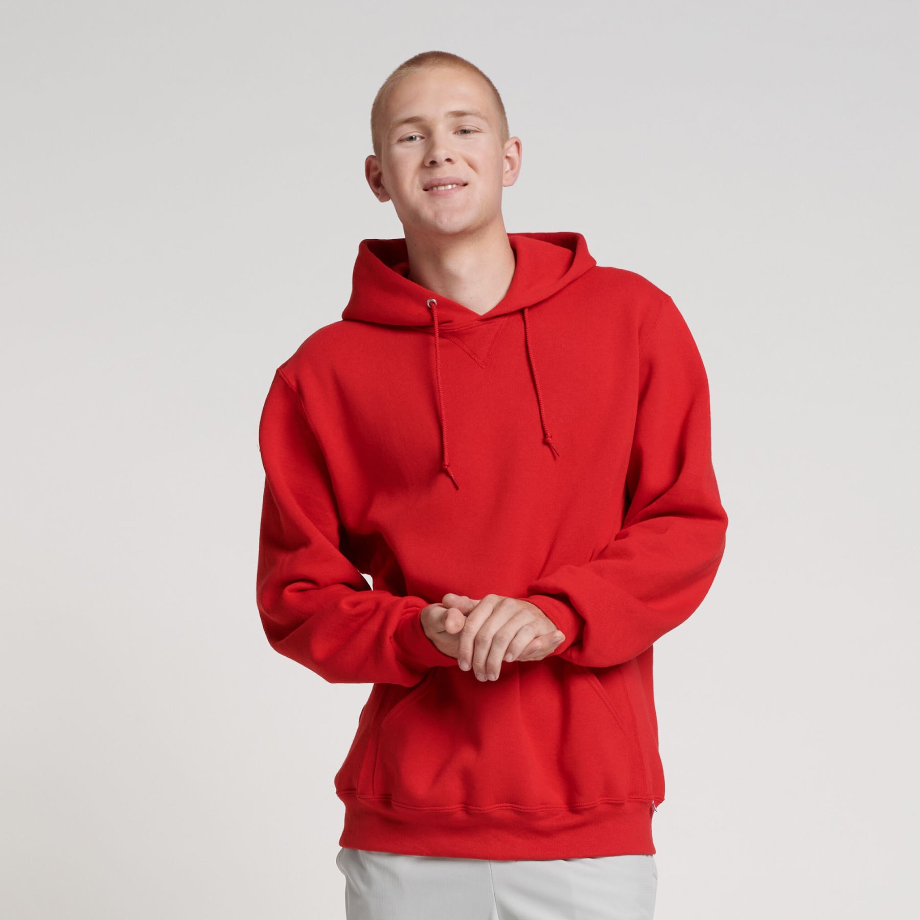 A person wearing a Russell Athletic DRI-POWER Adult Fleece Unisex Hoodie in True Red against a white background.