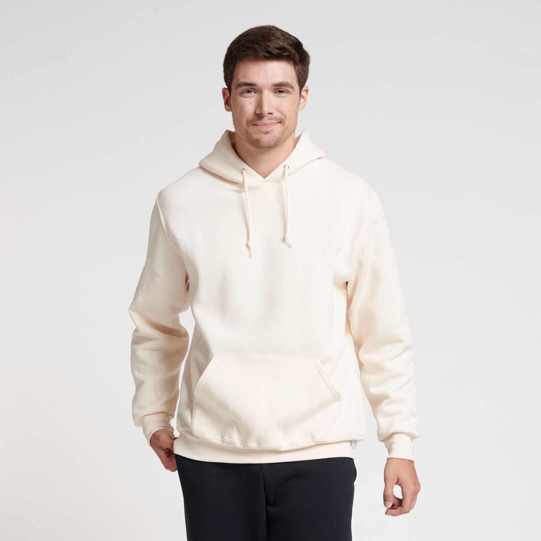 A man wearing a Russell Athletic DRI-POWER Adult Fleece Unisex Hoodie in Vintage White against a white background.
