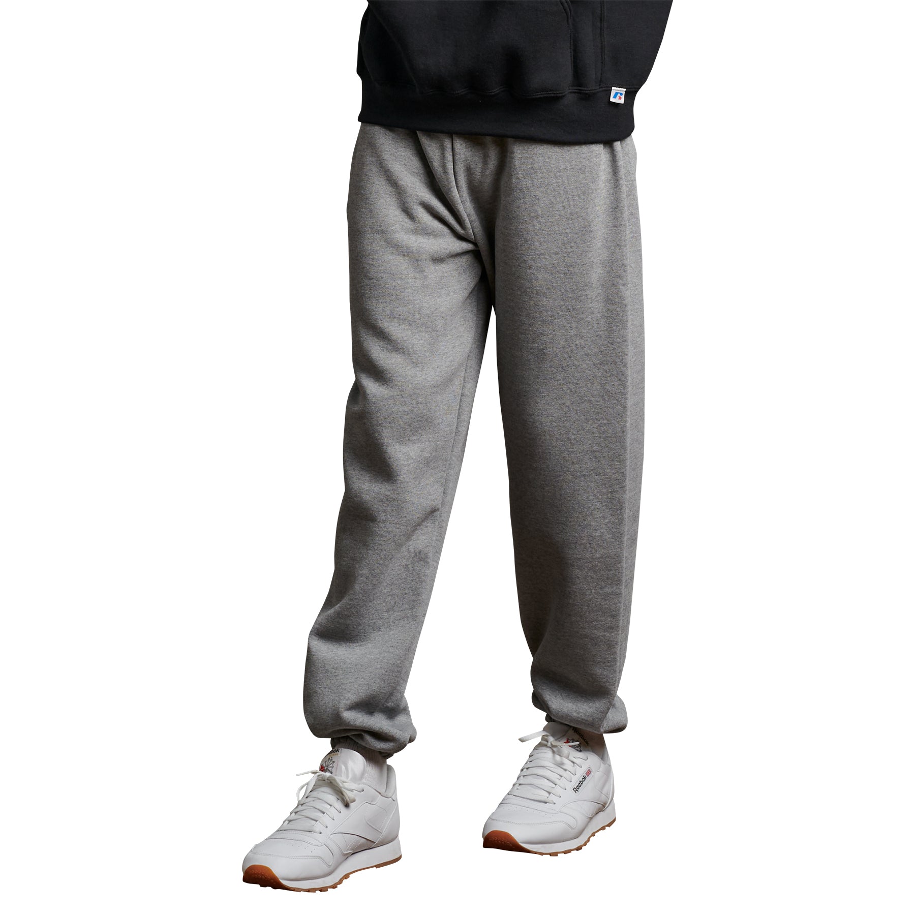 Russell Athletic DRI-POWER adult closed-bottom sweatpants in oxford grey worn with a black hoodie and white sneakers.