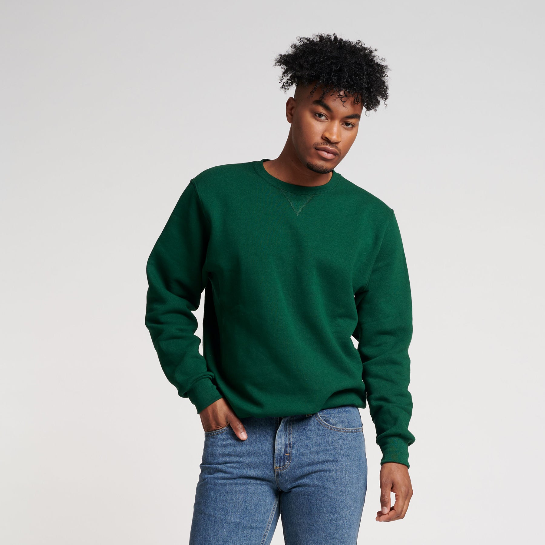 Man wearing a dark green Russell Athletic DRI-POWER Adult Fleece Crew sweatshirt with blue jeans.