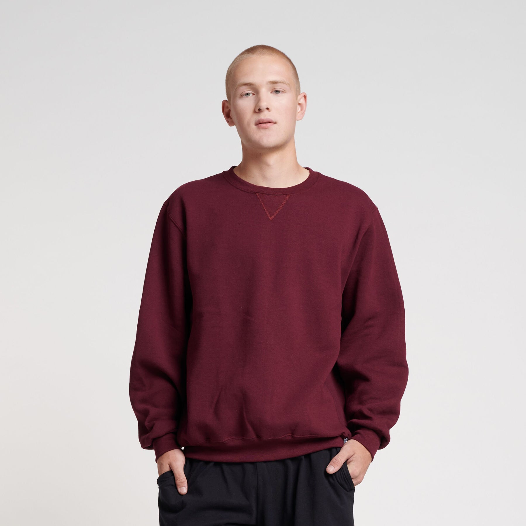 A man wearing a maroon Russell Athletic DRI-POWER Adult Fleece Crew sweatshirt against a white background.