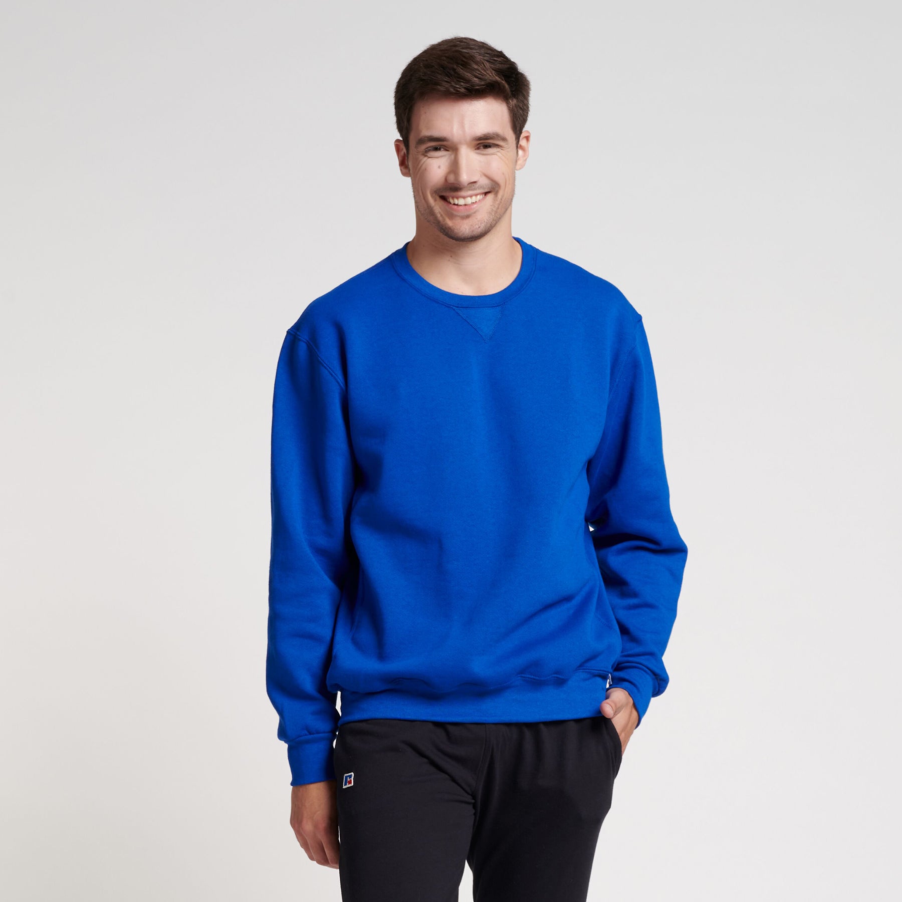 Man wearing a royal blue Russell Athletic DRI-POWER Adult Fleece Crew sweatshirt with black pants.