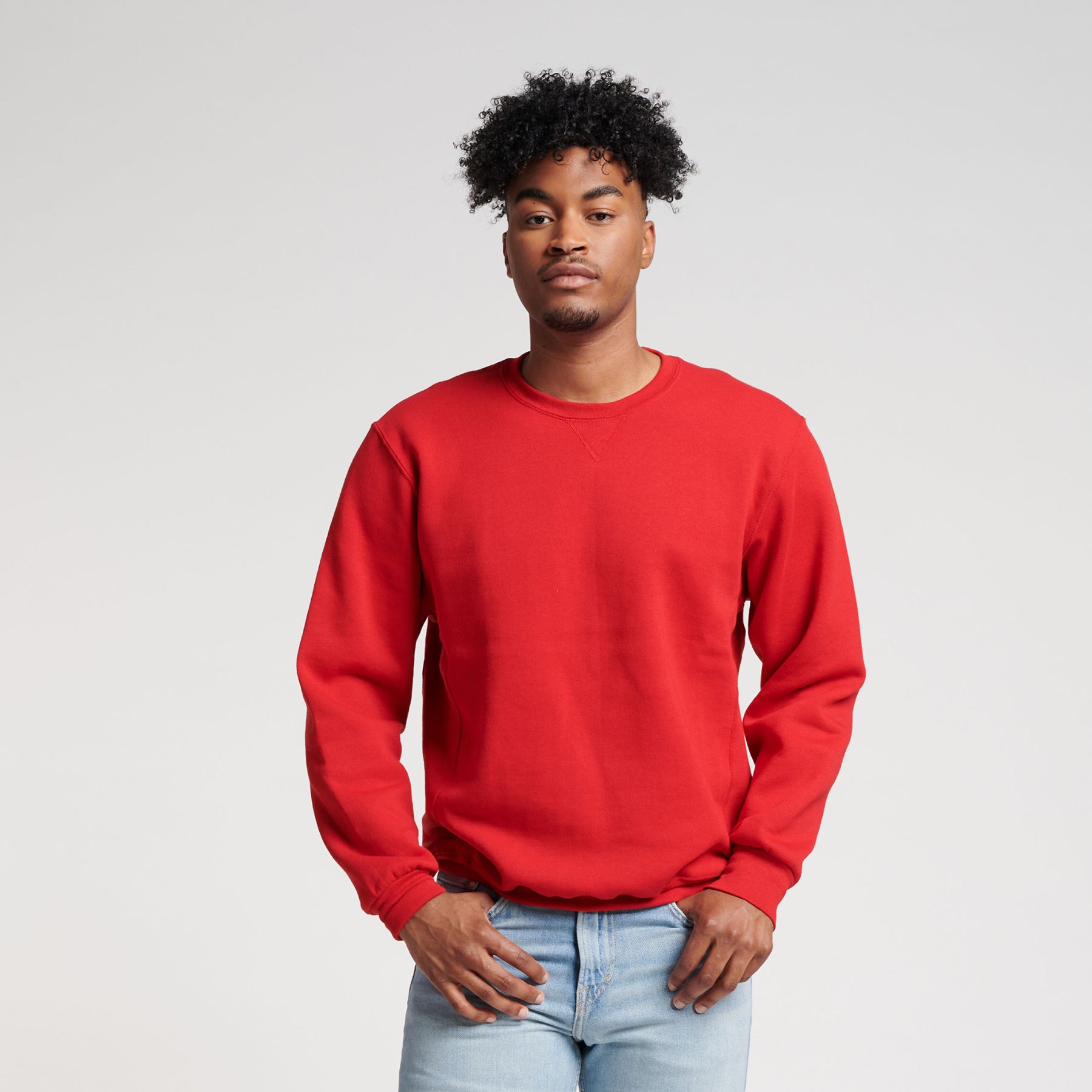 Man wearing a True Red Russell Athletic DRI-POWER Adult Fleece Crew sweatshirt with light wash jeans.