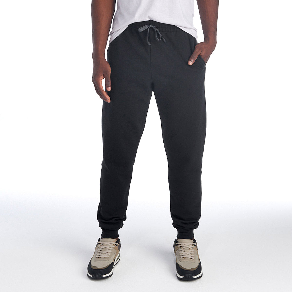 A person wearing black Jerzees NuBlend® Adult Pocketed Jogger Sweatpants with a drawstring waist and neutral sneakers.