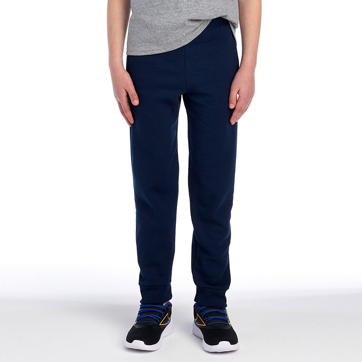 Youth wearing Jerzees NuBlend pocketed jogger sweatpants in J. Navy paired with athletic sneakers.