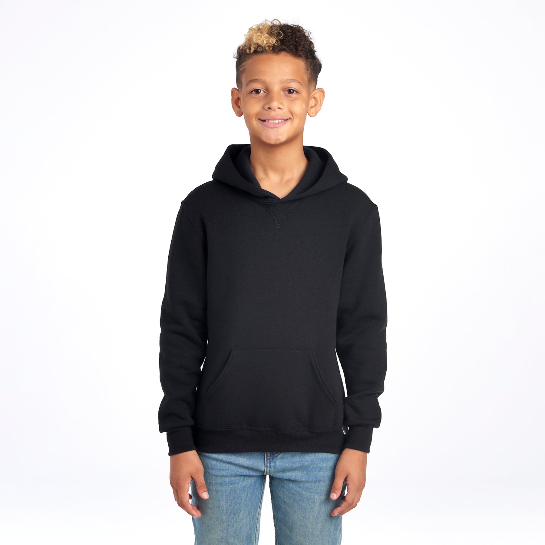 A boy wearing a black Russell Athletic DRI-POWER Youth Fleece Pullover Hoodie with jeans against a white background.