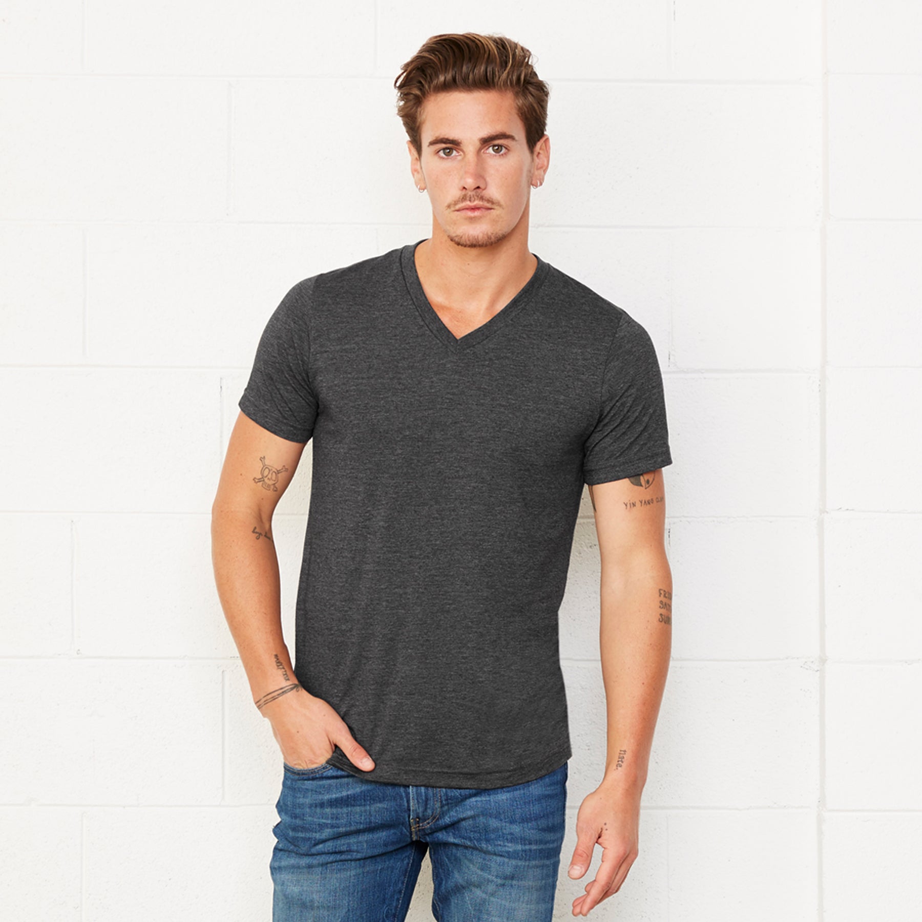 A model wearing a Bella+Canvas Unisex Heather CVC Short Sleeve V-Neck Tee in Dark Grey Heather.