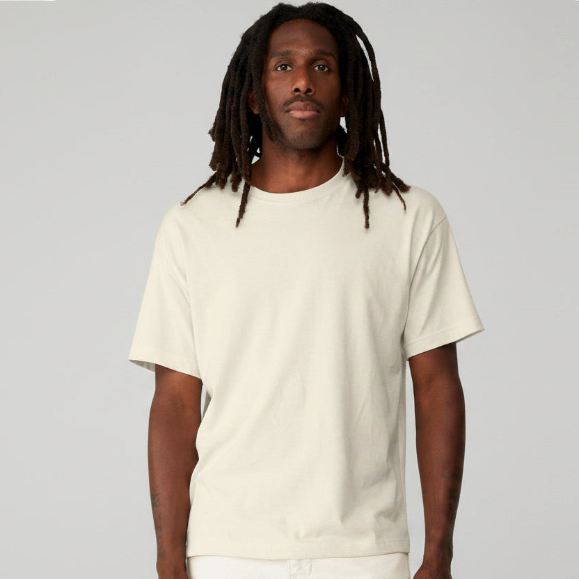 Model wearing a natural Bella + Canvas Unisex 6 oz Heavyweight Tee, a basic cream-colored crewneck t-shirt.