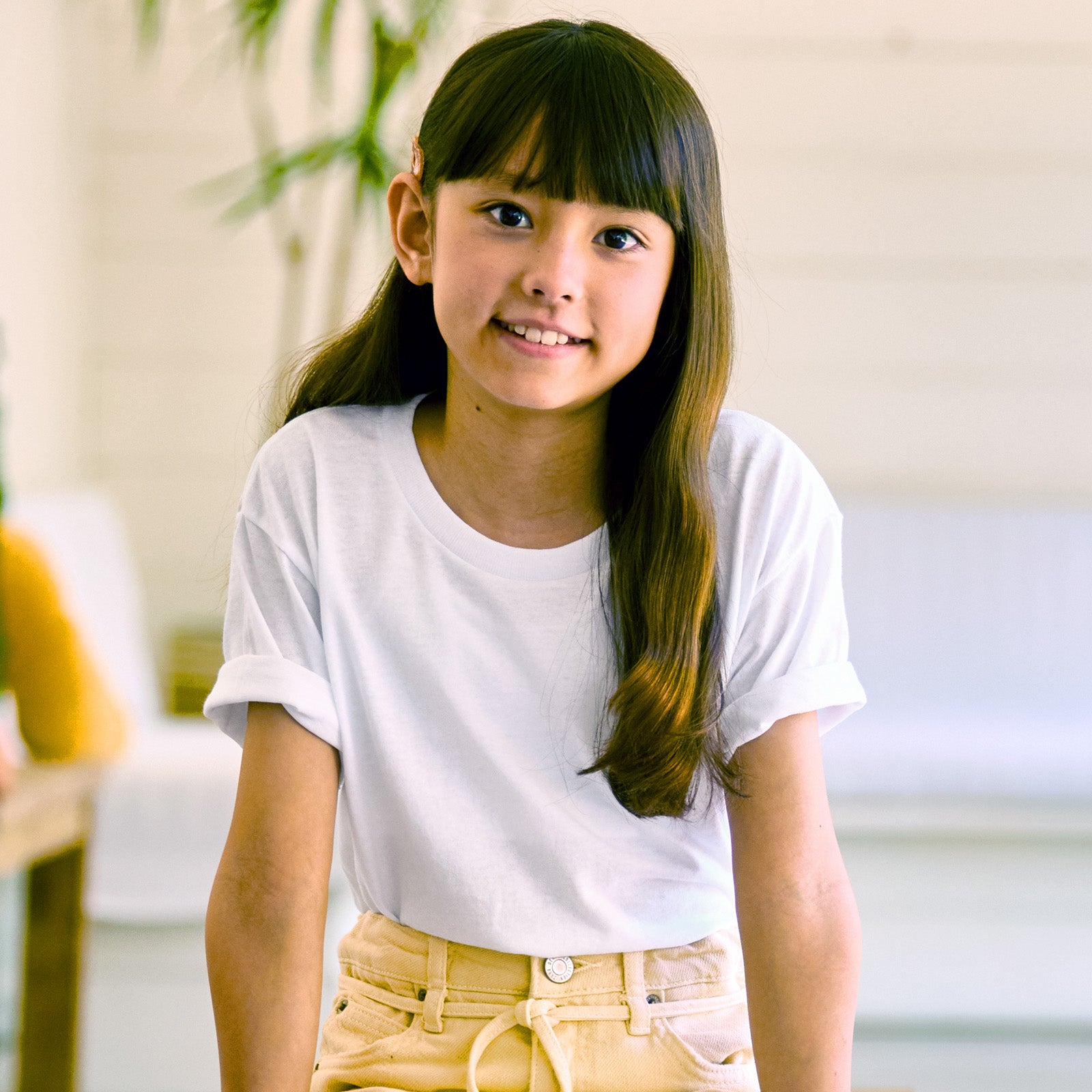 A young girl smiling while wearing a white Jerzees Dri-Power Youth T-Shirt.