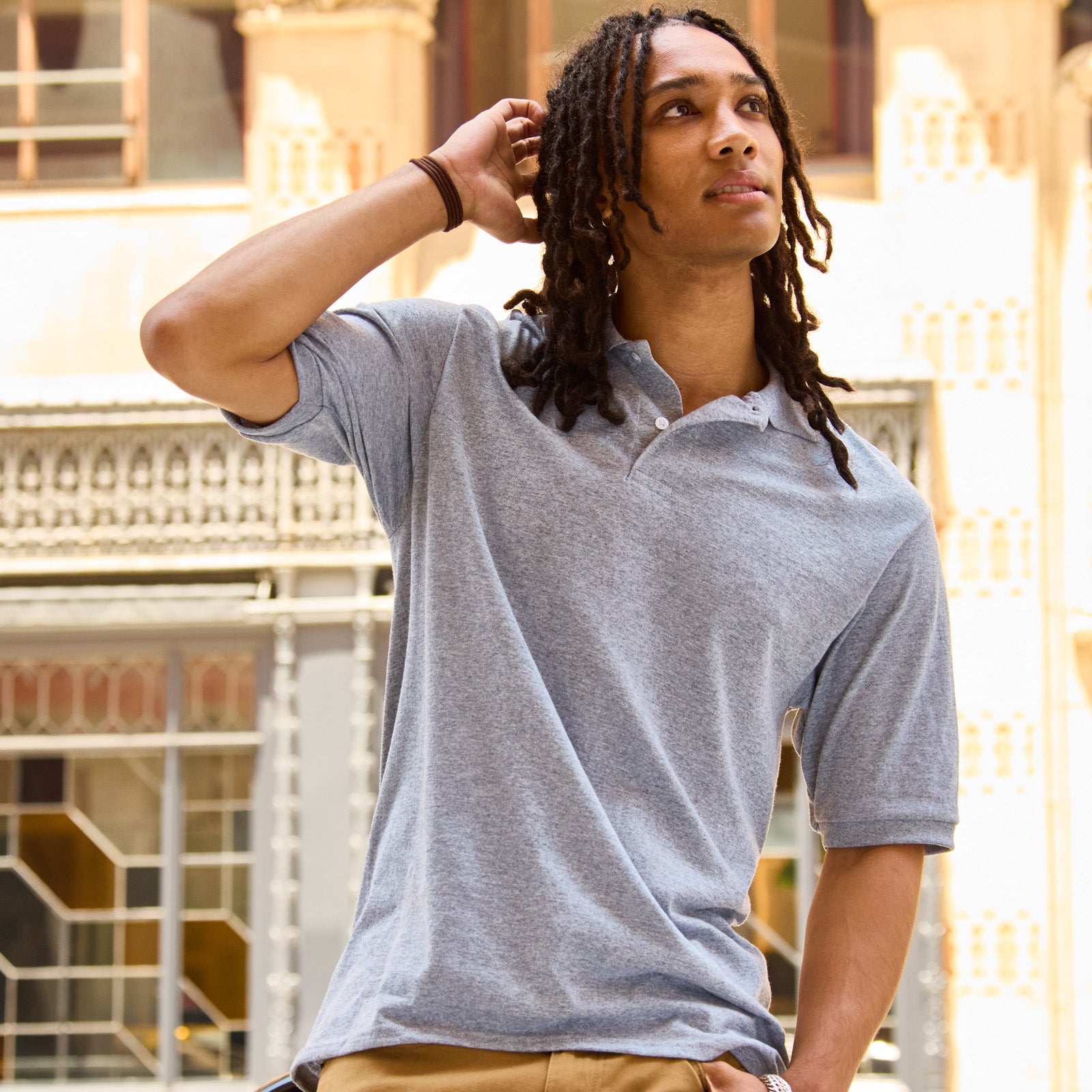 Young man with dreadlocks wearing an Oxford Jerzees Dri-Power Sport Shirt outdoors.