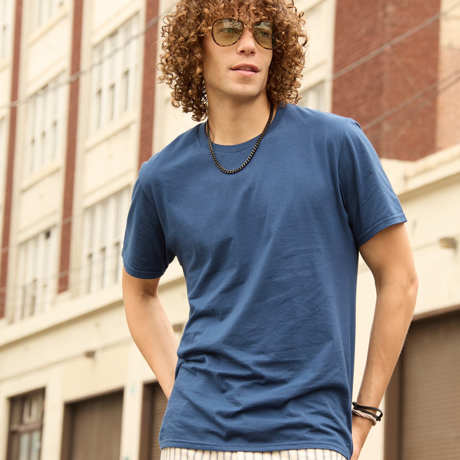 Curly-haired man wearing a Jerzees Premium Combed Ring-Spun Cotton Unisex T-Shirt in Washed Navy.