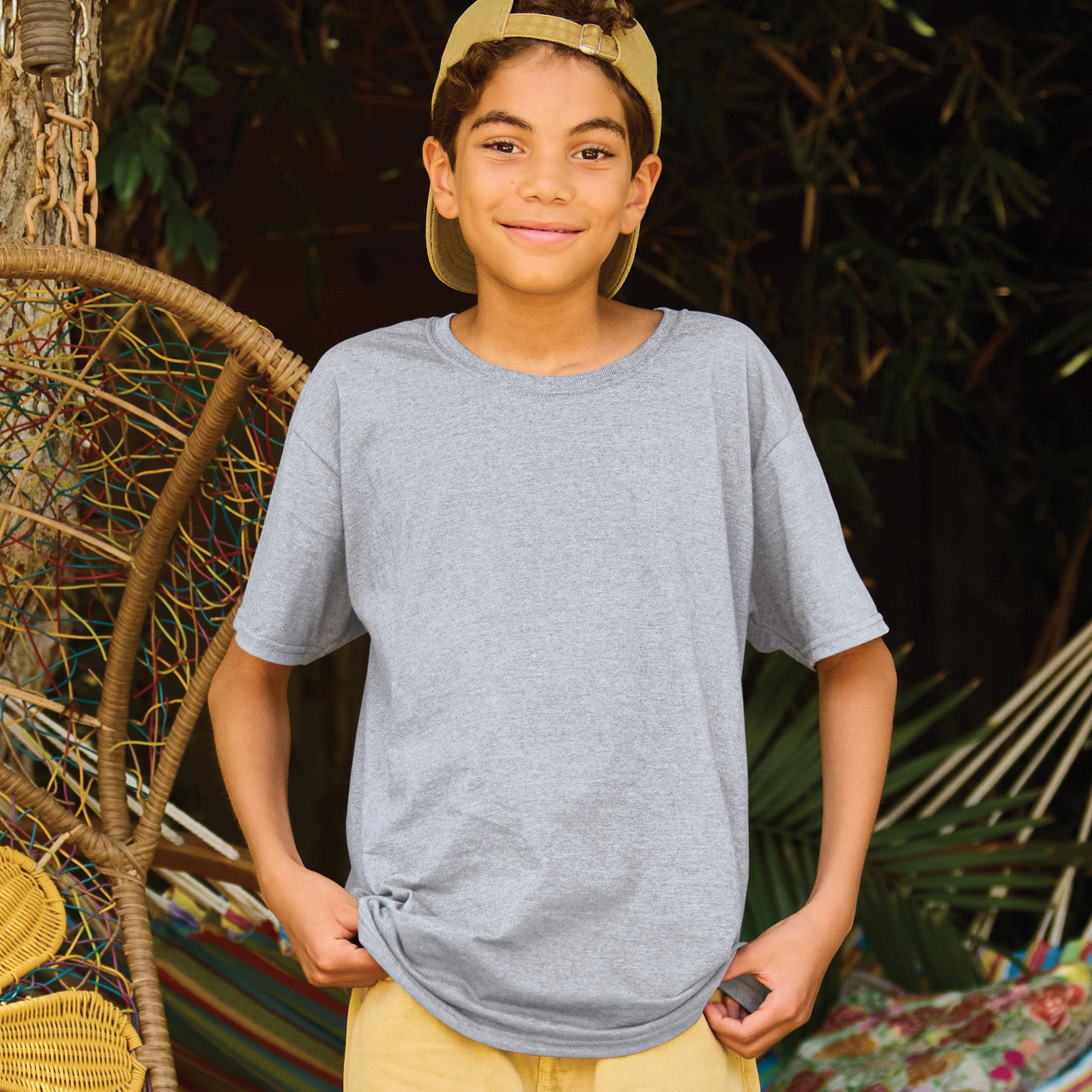A young boy wearing a grey Jerzees Ultimate Ring-Spun Youth T-Shirt in Athletic Heather.