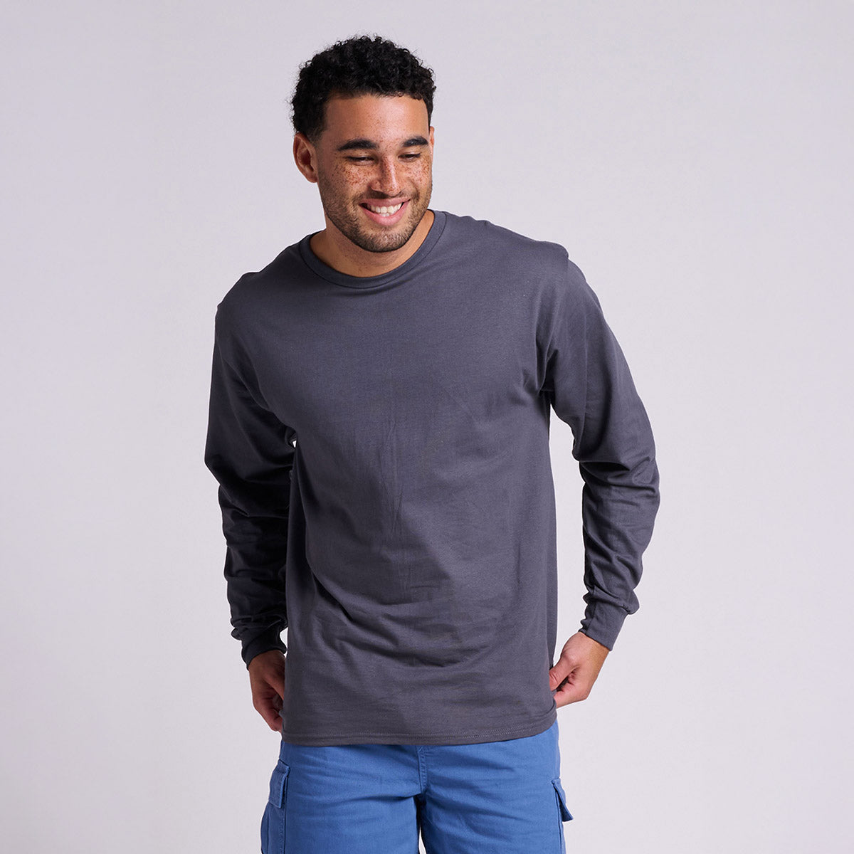 Smiling man wearing a charcoal grey Jerzees Classics Unisex Long Sleeve t-shirt against a light background.
