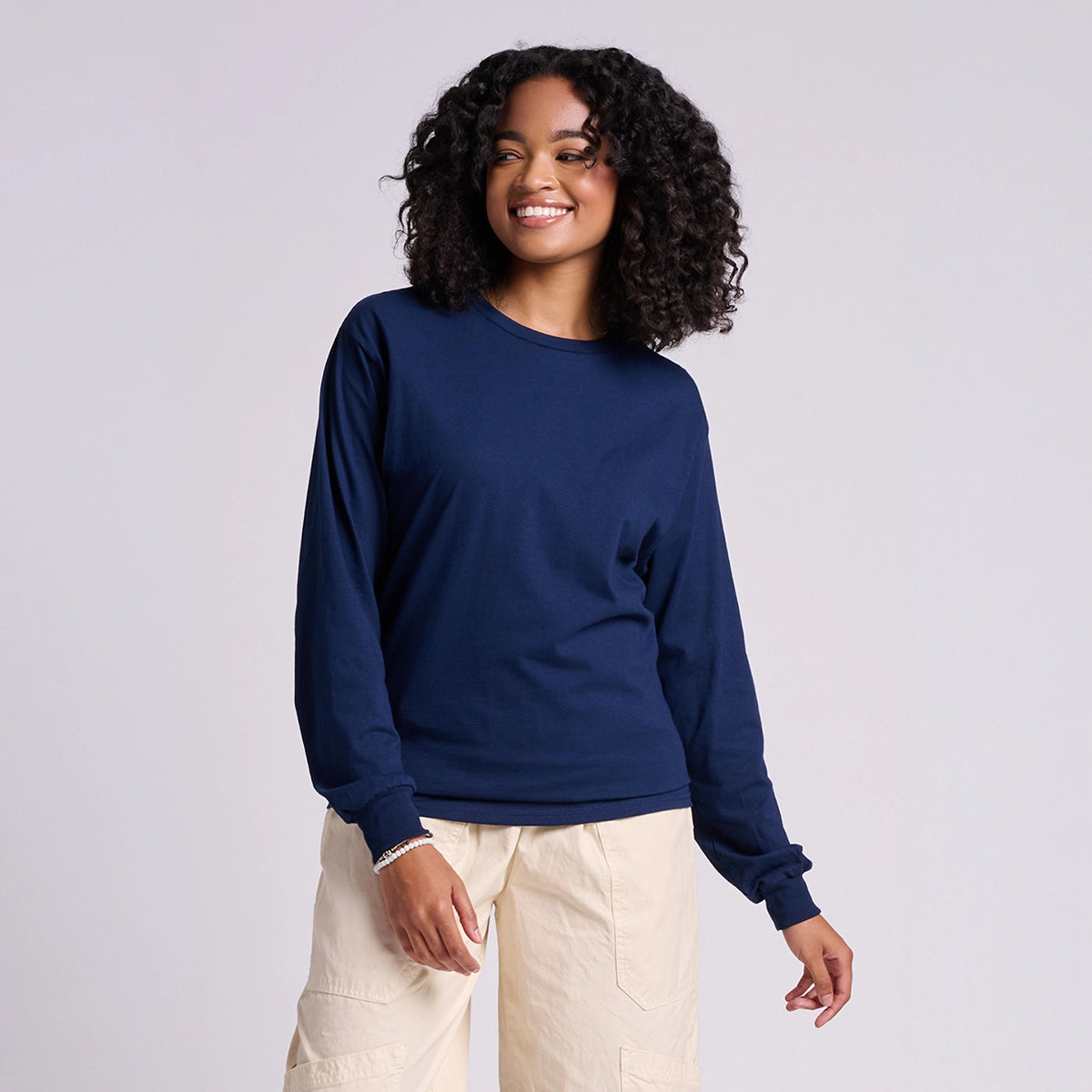 Woman wearing a navy blue long-sleeve shirt and beige pants on a light gray background