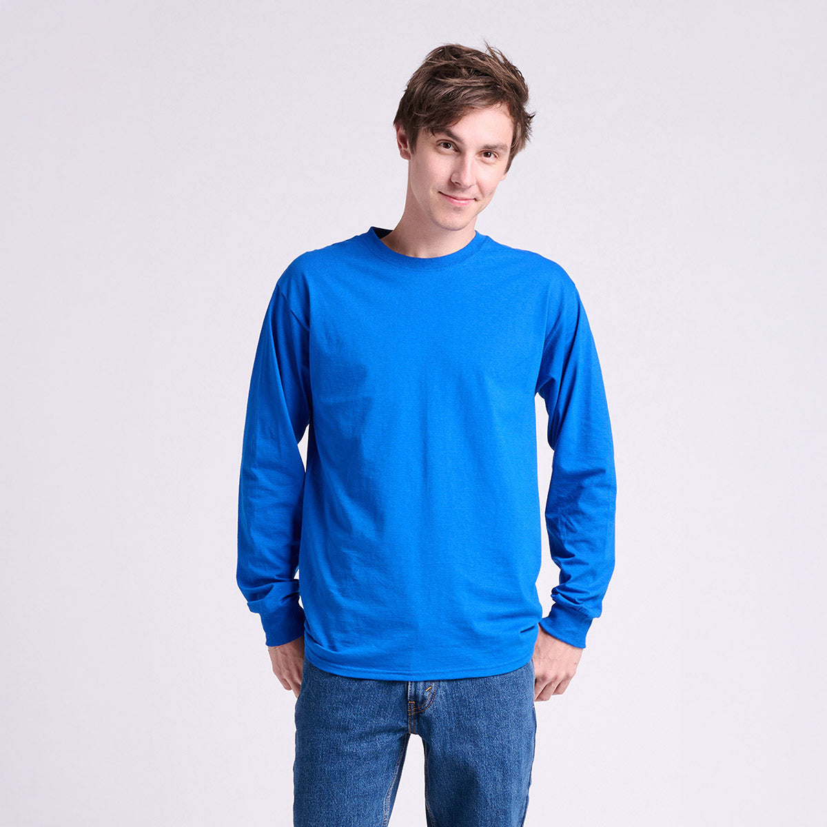 Young man wearing a royal blue Jerzees Classics Unisex Long Sleeve T-shirt against a white background.