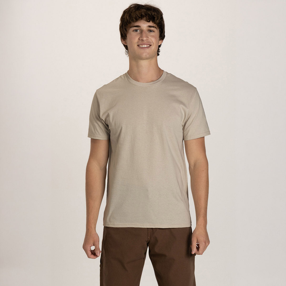 Young man wearing a putty-colored Jerzees Classics unisex crewneck t-shirt against a white background.