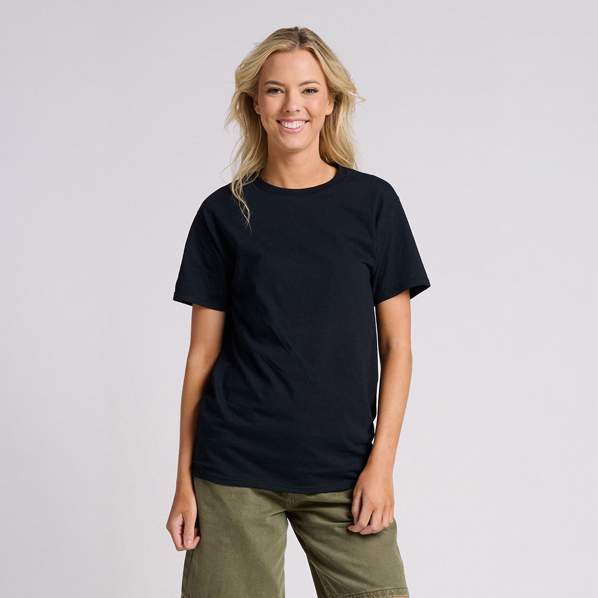 A blonde woman wearing a Jerzees Classics Unisex T-Shirt in black ink paired with olive green shorts.