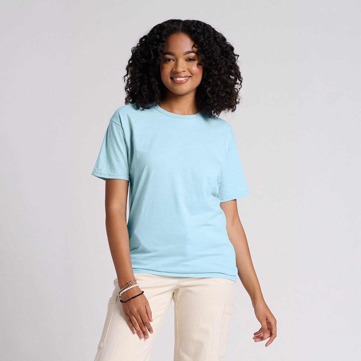 Woman wearing a Jerzees Classics Unisex T-Shirt in Breezy Blue with light-colored pants.