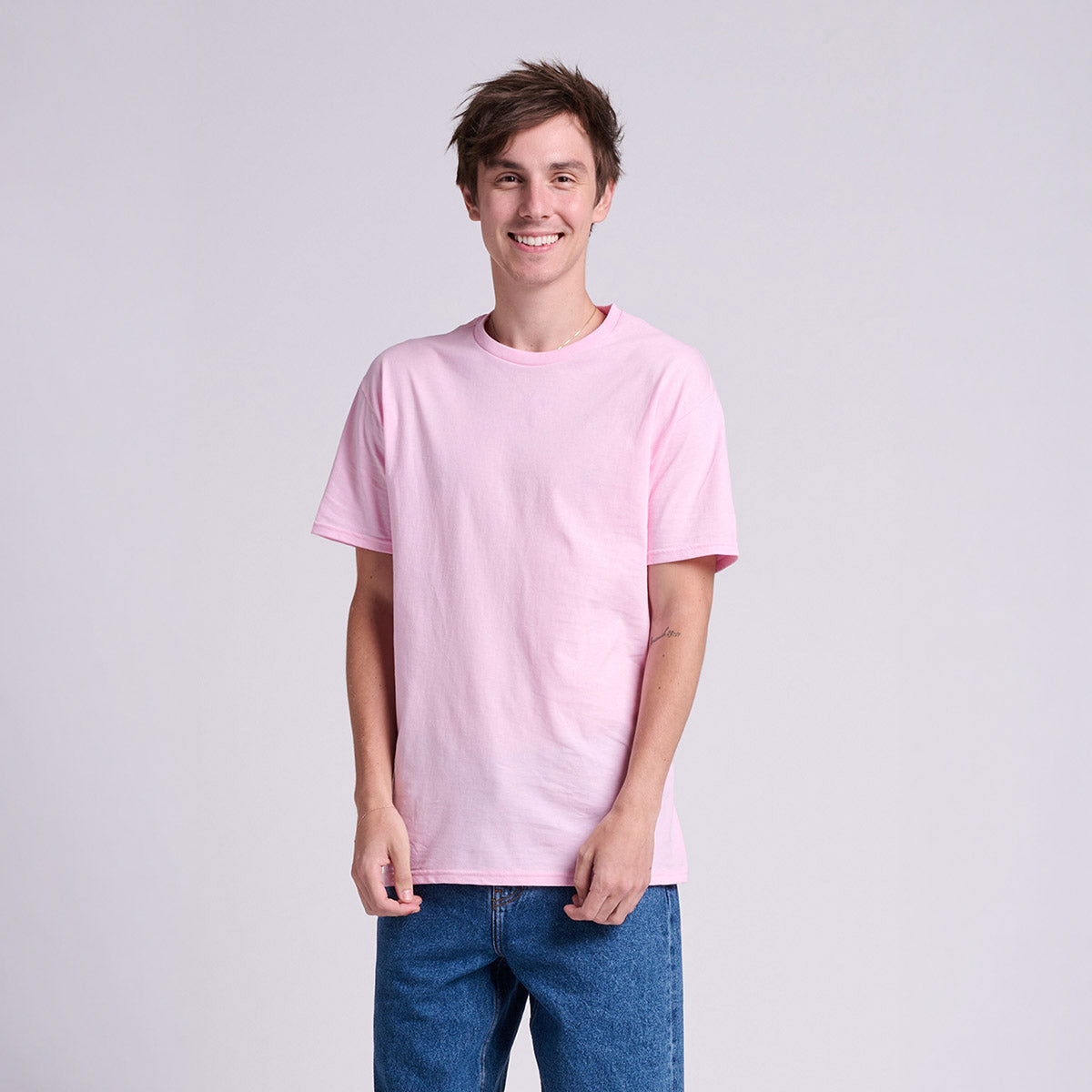A man wearing a Classic Pink Jerzees Classics Unisex T-Shirt standing against a neutral background.