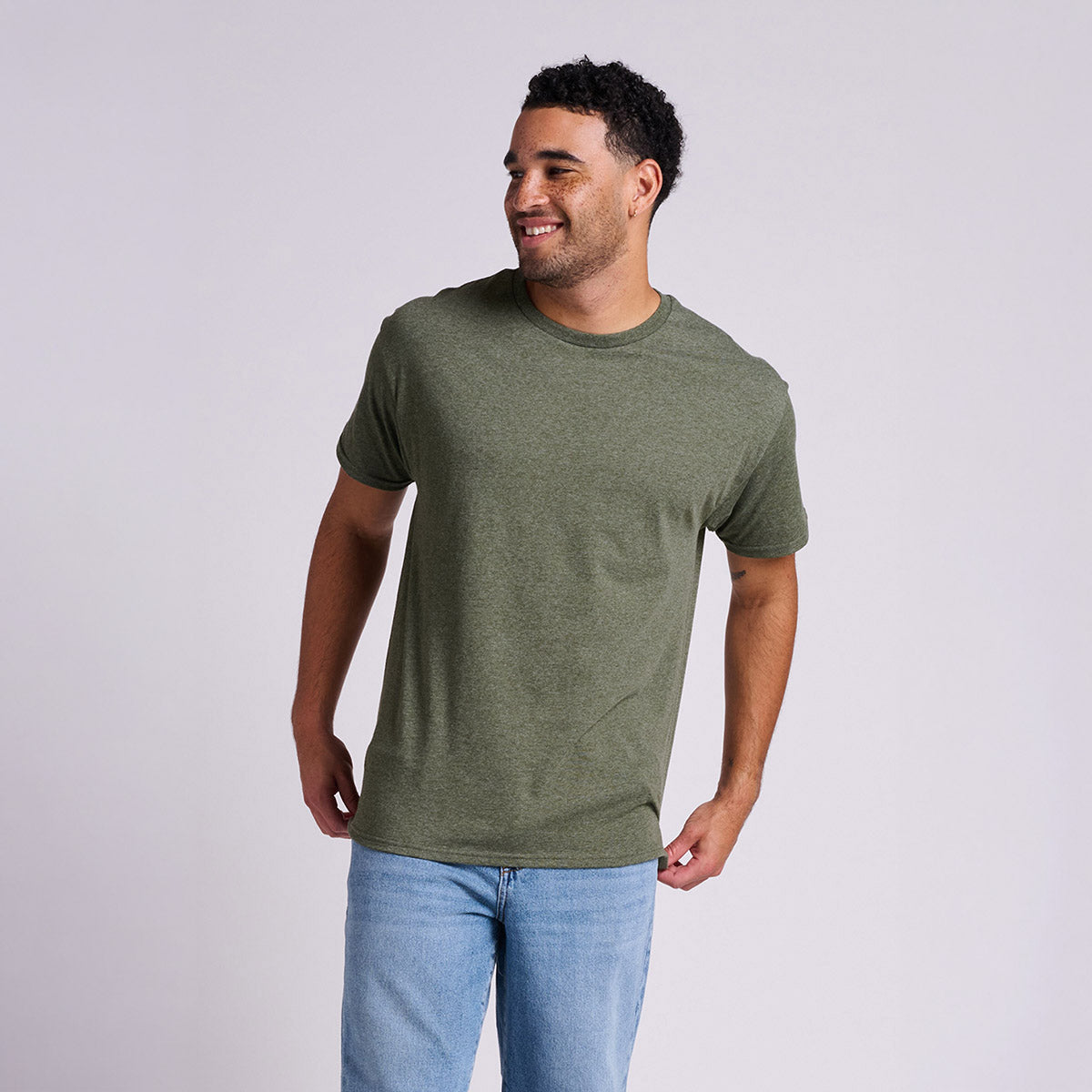 Man wearing a Jerzees Classics Unisex T-Shirt in Military Green Heather against a grey background.