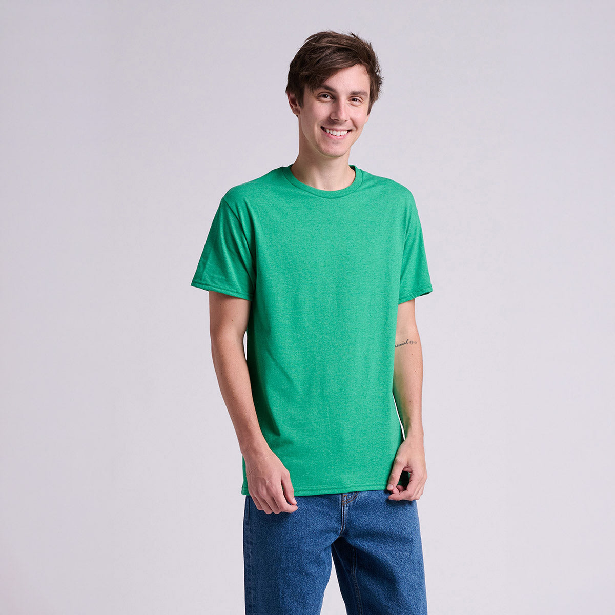 A young man wearing a Jerzees Classics Unisex T-Shirt in Retro Heather Green against a light gray background.