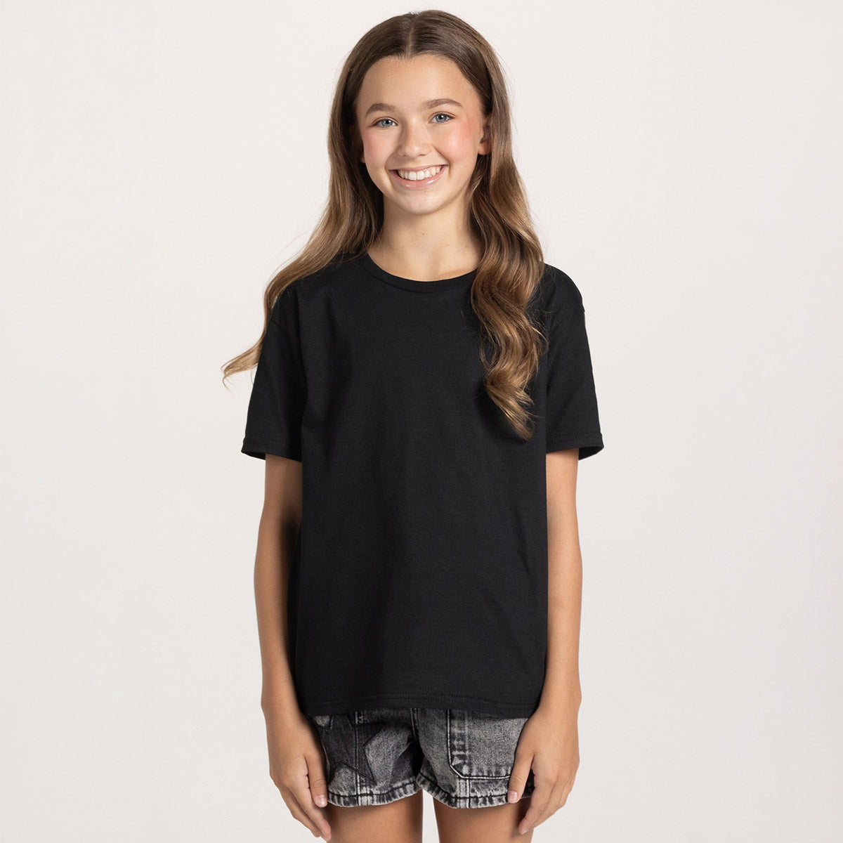 Youth girl smiling while wearing a black Jerzees Classics T-Shirt.
