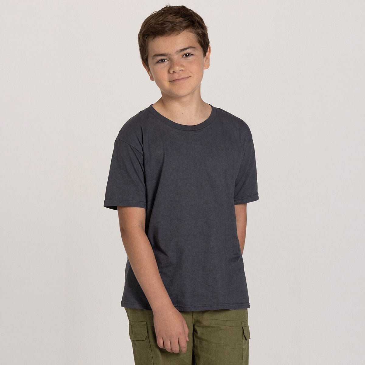 A young boy wearing a charcoal grey Jerzees Classics Youth T-shirt against a light grey background.