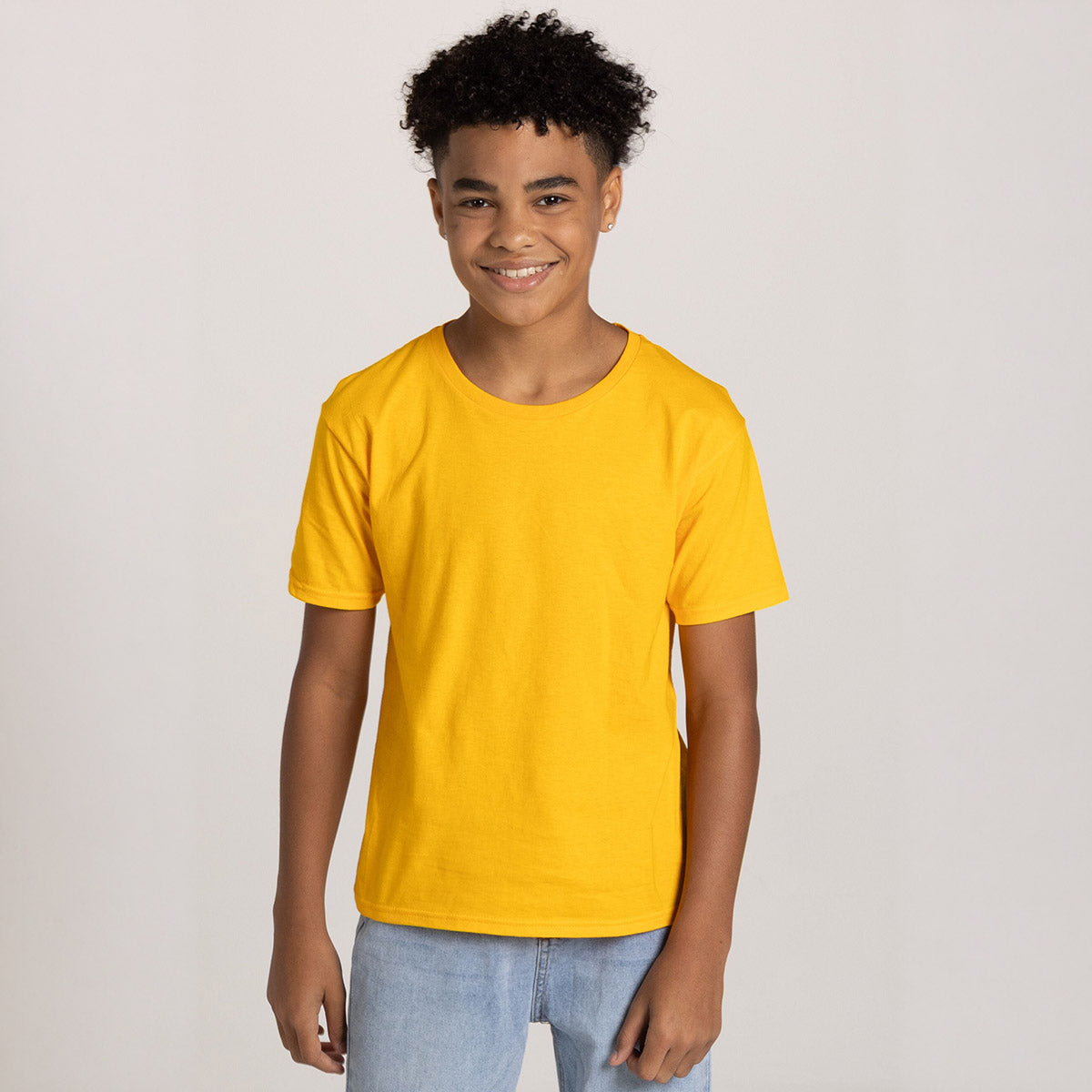 Youth boy wearing a gold Jerzees Classics Youth T-Shirt standing against a plain background.