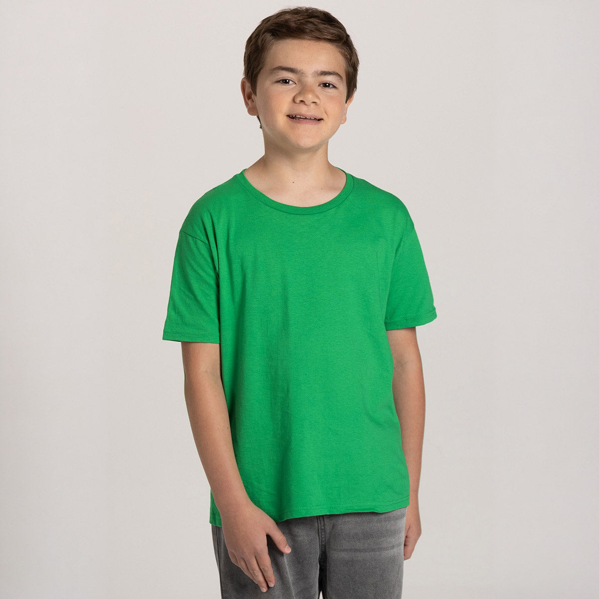 A young boy wearing a Kelly green Jerzees Classics Youth T-Shirt against a white background.