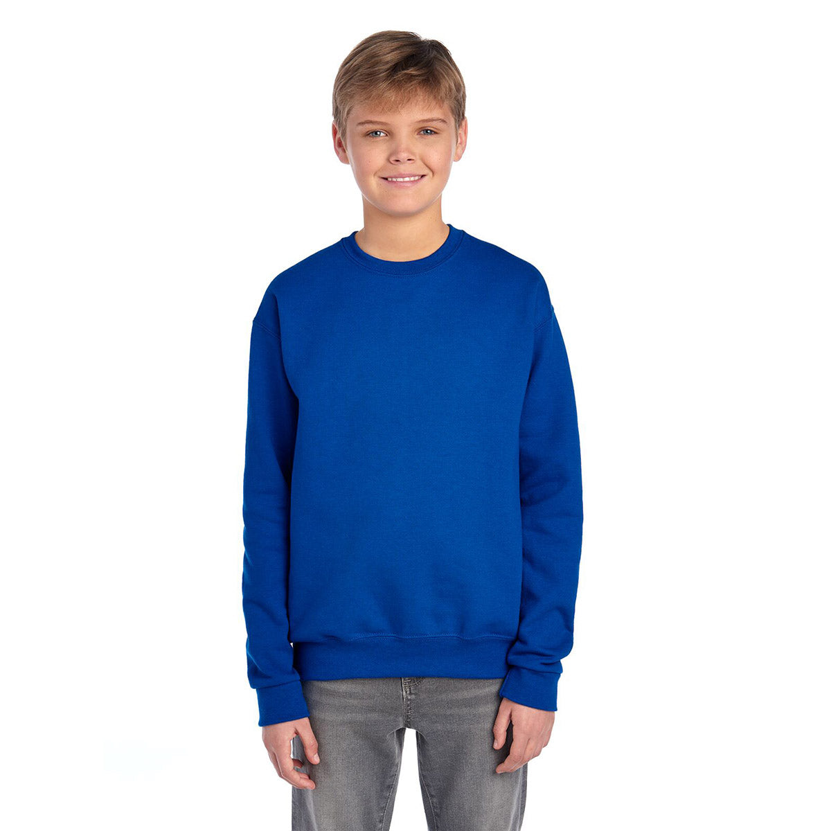 A boy wearing a royal blue Jerzees NuBlend® Youth Sweatshirt with a crew neck, isolated on a white background.