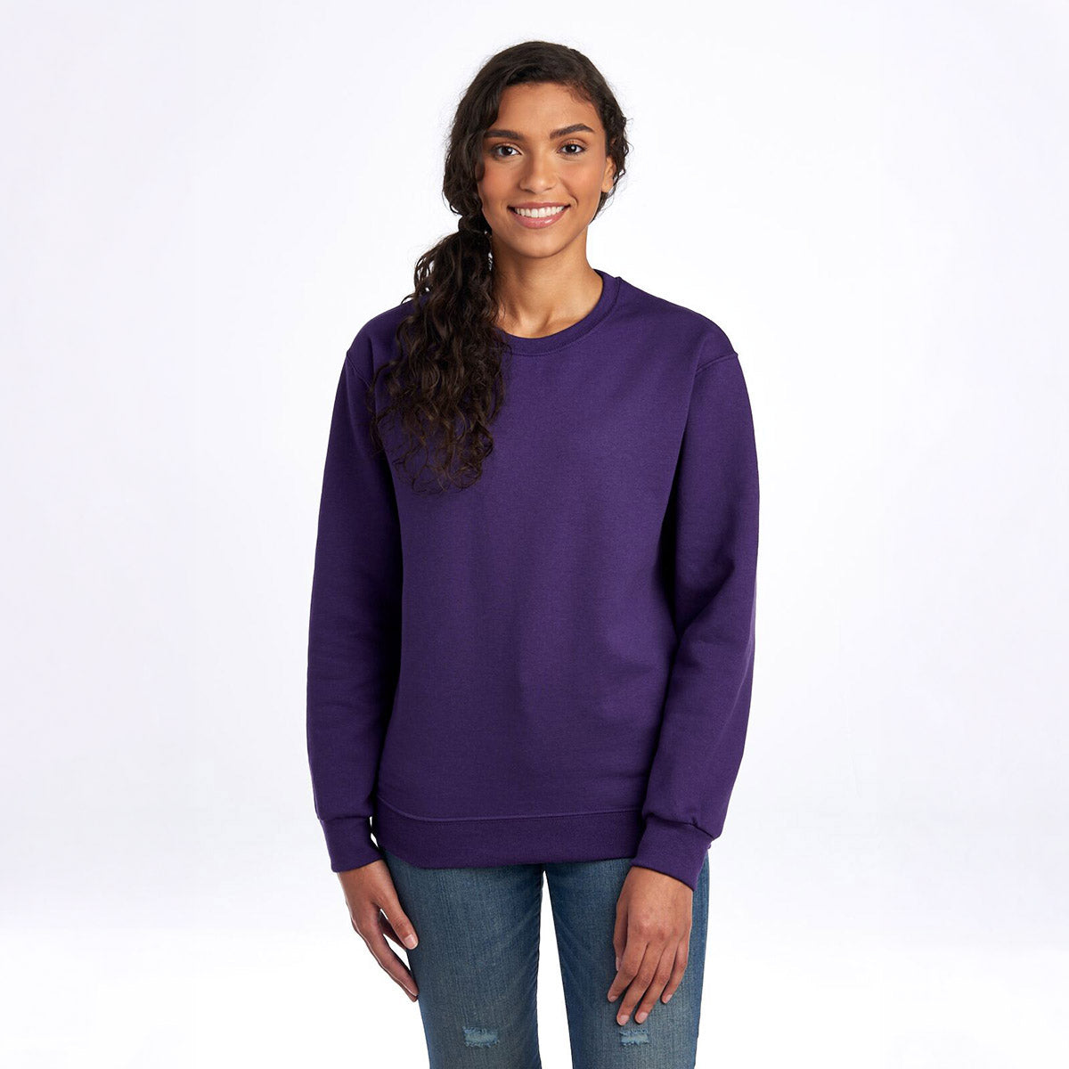 A woman wearing a deep purple Jerzees NuBlend Adult Sweatshirt against a white background.