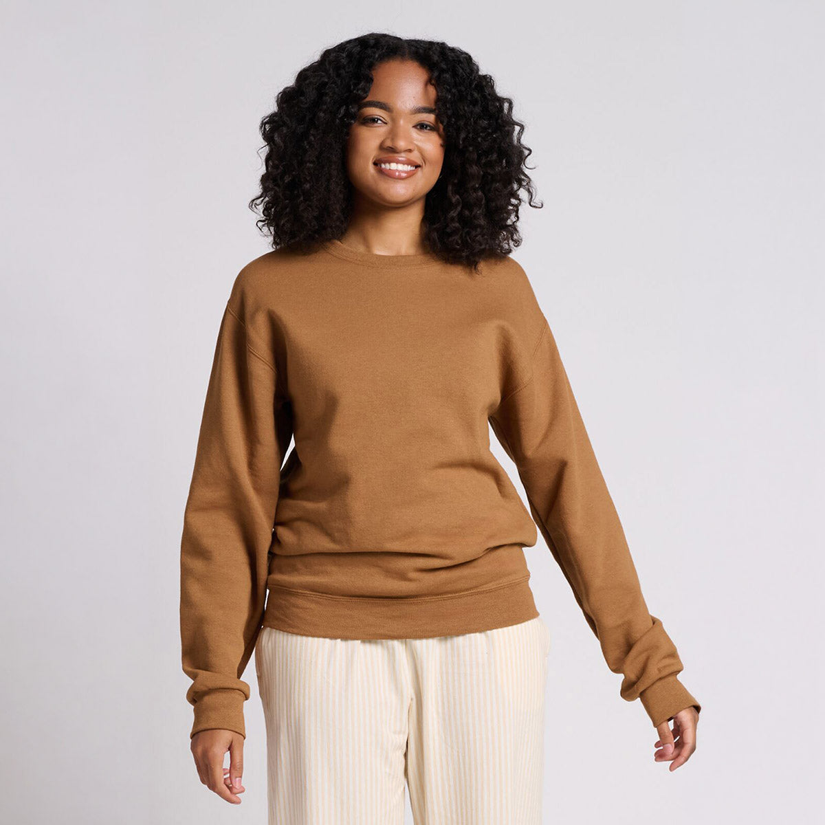 Woman smiling while wearing a Jerzees NuBlend® Adult Sweatshirt in Golden Pecan.
