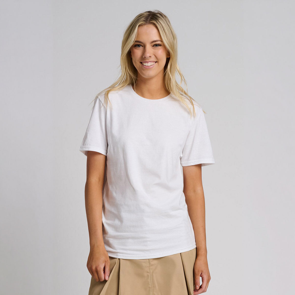 A woman wearing a white Jerzees Premium Combed Ring-Spun Cotton Unisex T-Shirt against a neutral background.