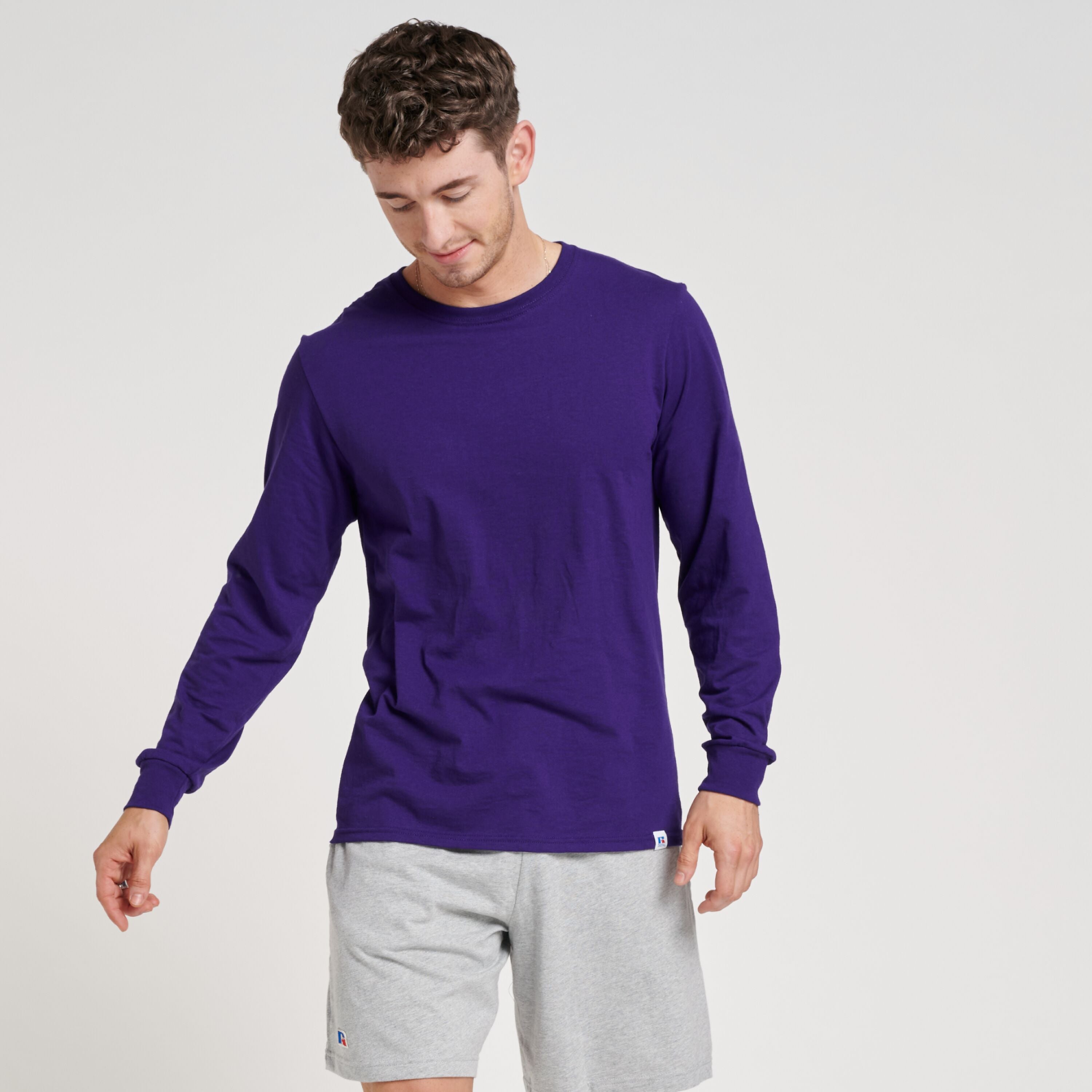 Russell Athletic DRI-POWER CVC Performance unisex long-sleeve t-shirt in purple worn with grey shorts.
