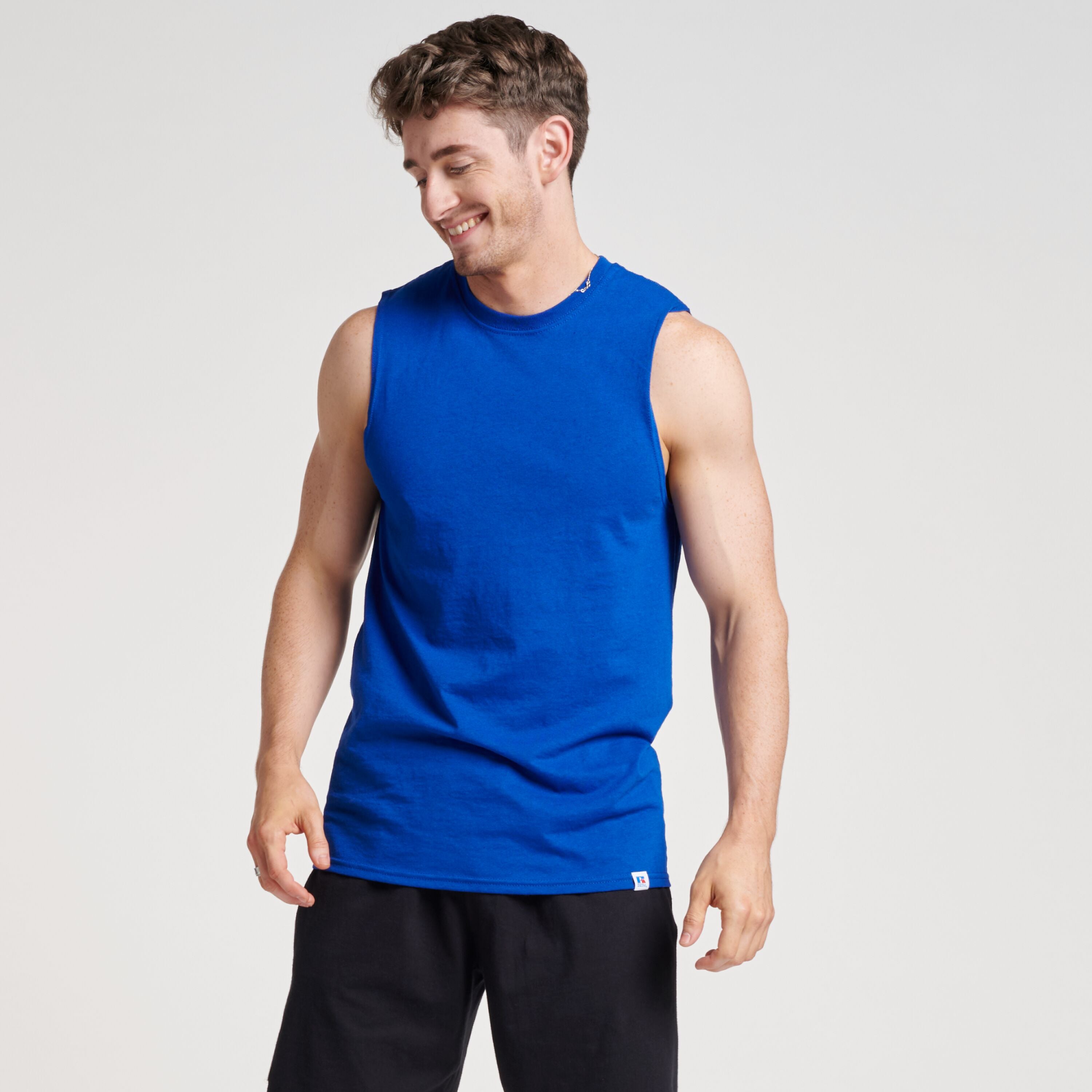 A man wearing a royal blue Russell Athletic DRI-POWER CVC Performance unisex muscle T-shirt with black shorts.