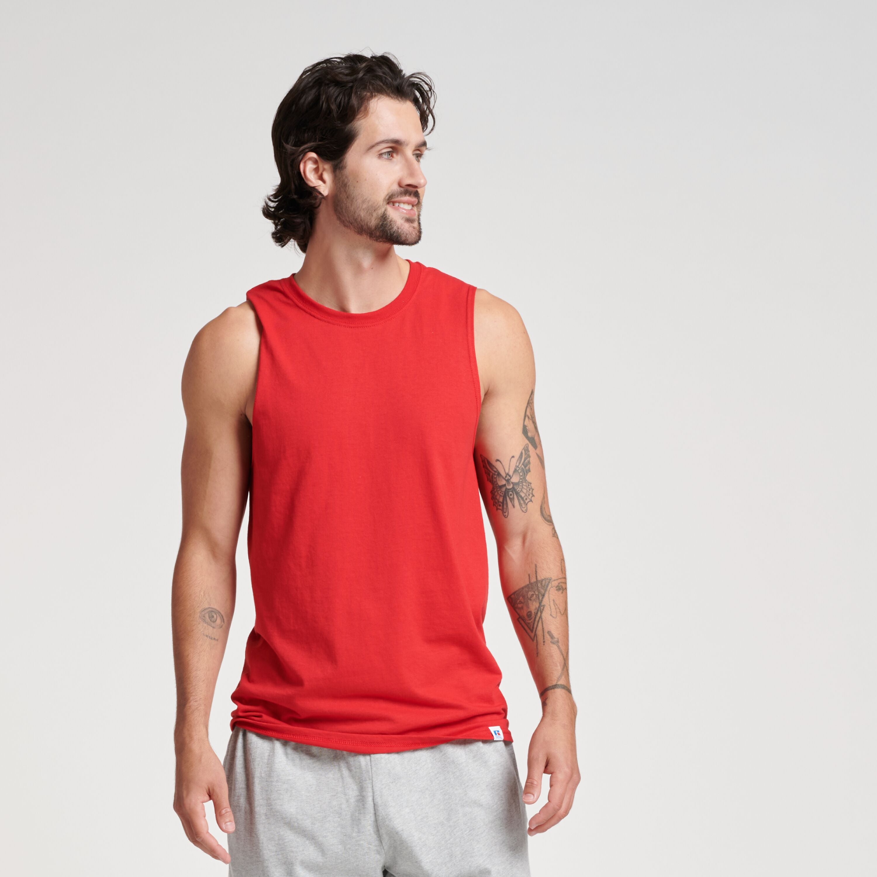 A man wearing a Russell Athletic DRI-POWER CVC Performance unisex muscle t-shirt in True Red with grey shorts.