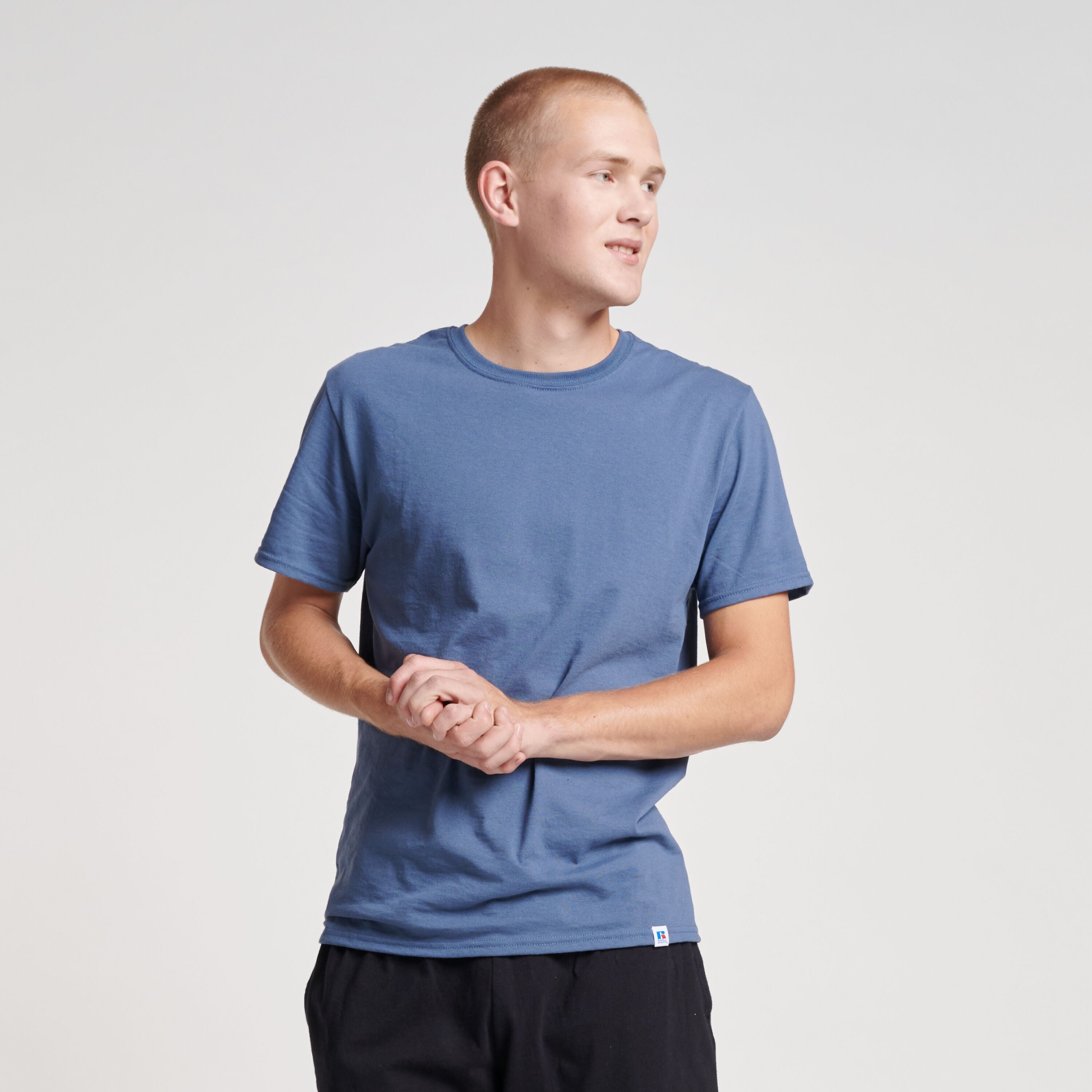 A man wearing a Vintage Blue Russell Athletic DRI-POWER® CVC Performance Unisex T-Shirt against a light grey background.