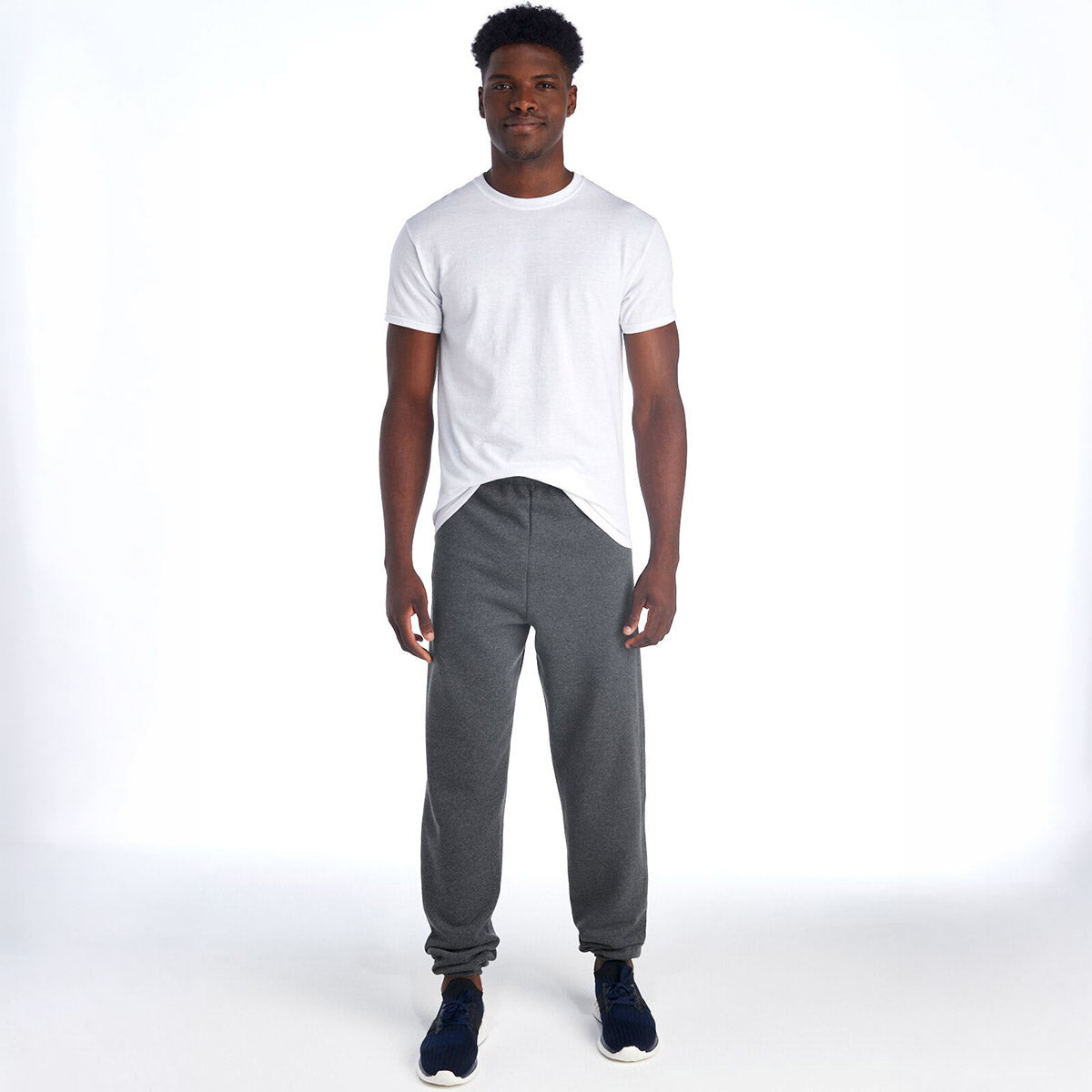 A man wears Jerzees NuBlend® Adult Sweatpants in Athletic Heather with a white t-shirt, standing against a white background.