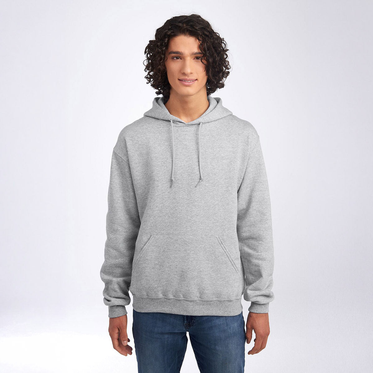 Young man wearing a Jerzees NuBlend Unisex Hooded Sweatshirt in Athletic Heather with a front kangaroo pocket.