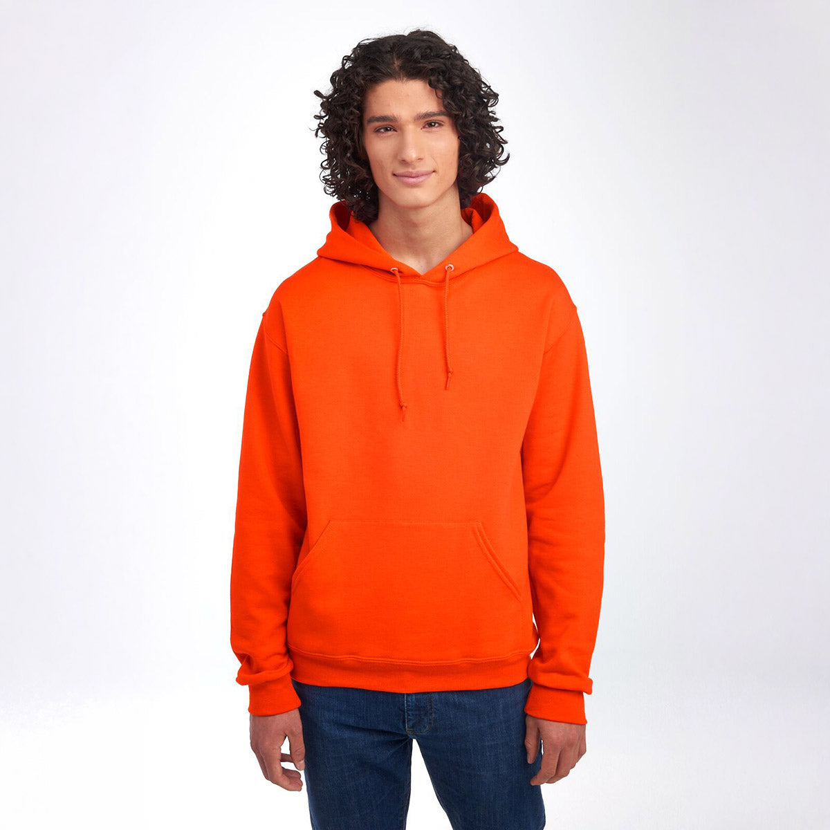 A man with curly hair wearing a Burnt Orange Jerzees NuBlend Unisex Hooded Sweatshirt against a white background.
